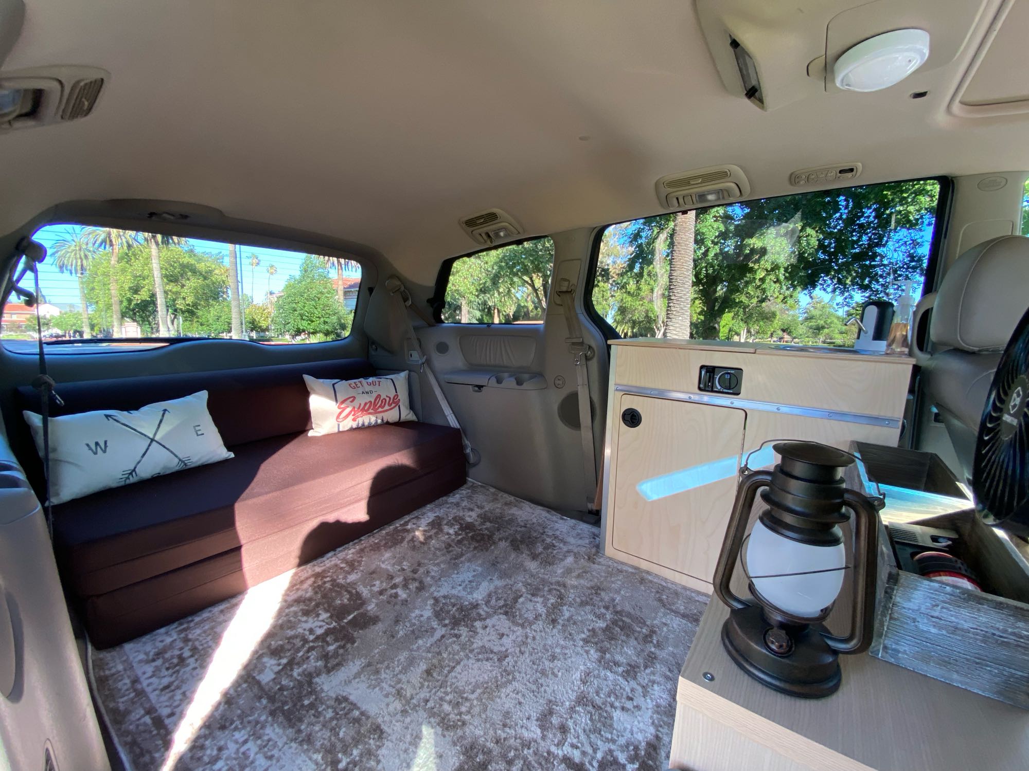 This customized van interior, ideal for an RV rental, showcases a comfy bed, storage, and homey touches for road trips.. Custom Camper 2004