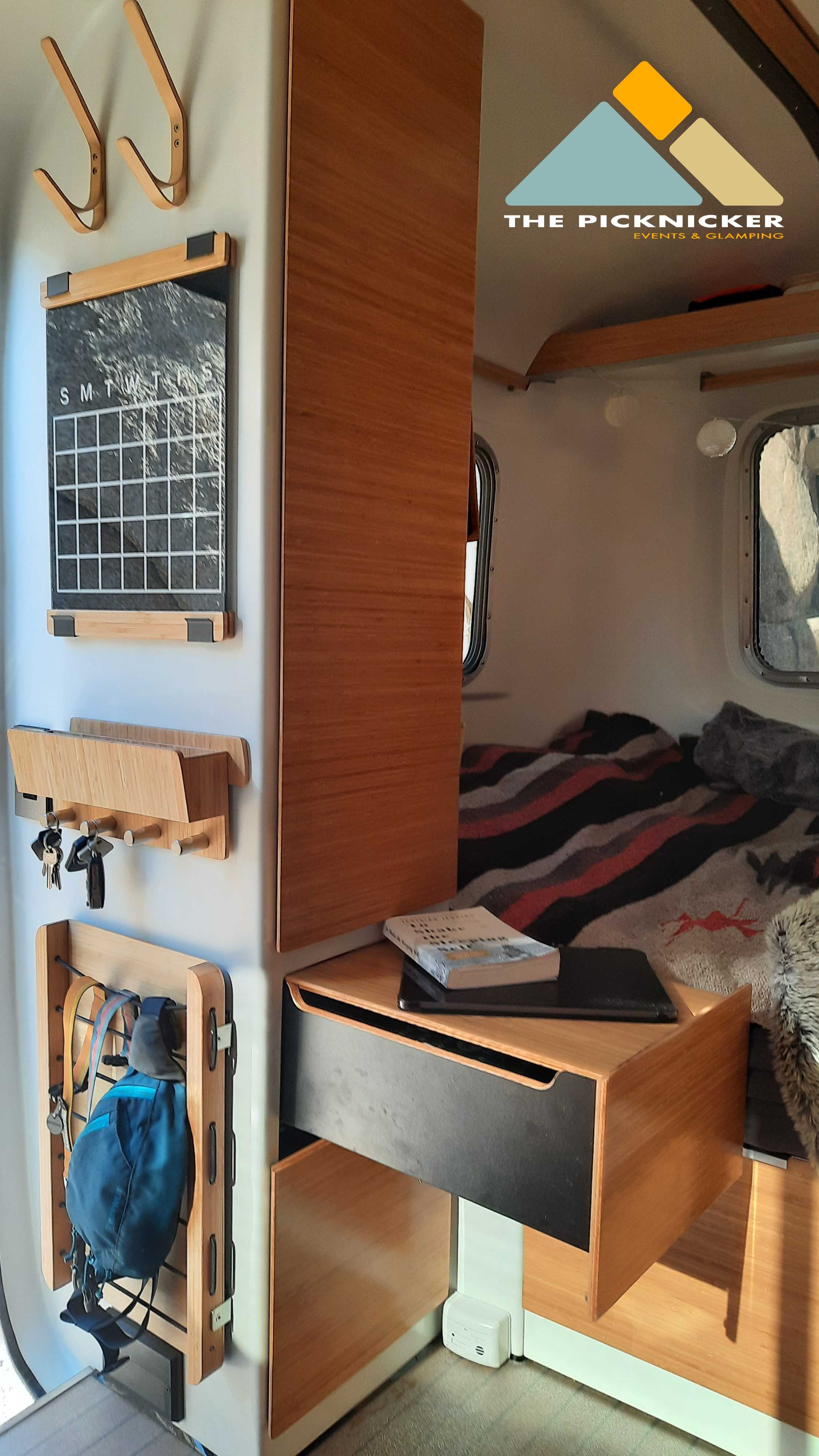 Cozy RV rental interior with practical wall storage: hooks, calendar, key holder, and bedside table.. Burro Vintage (OWNER TOWING ONLY) 1982