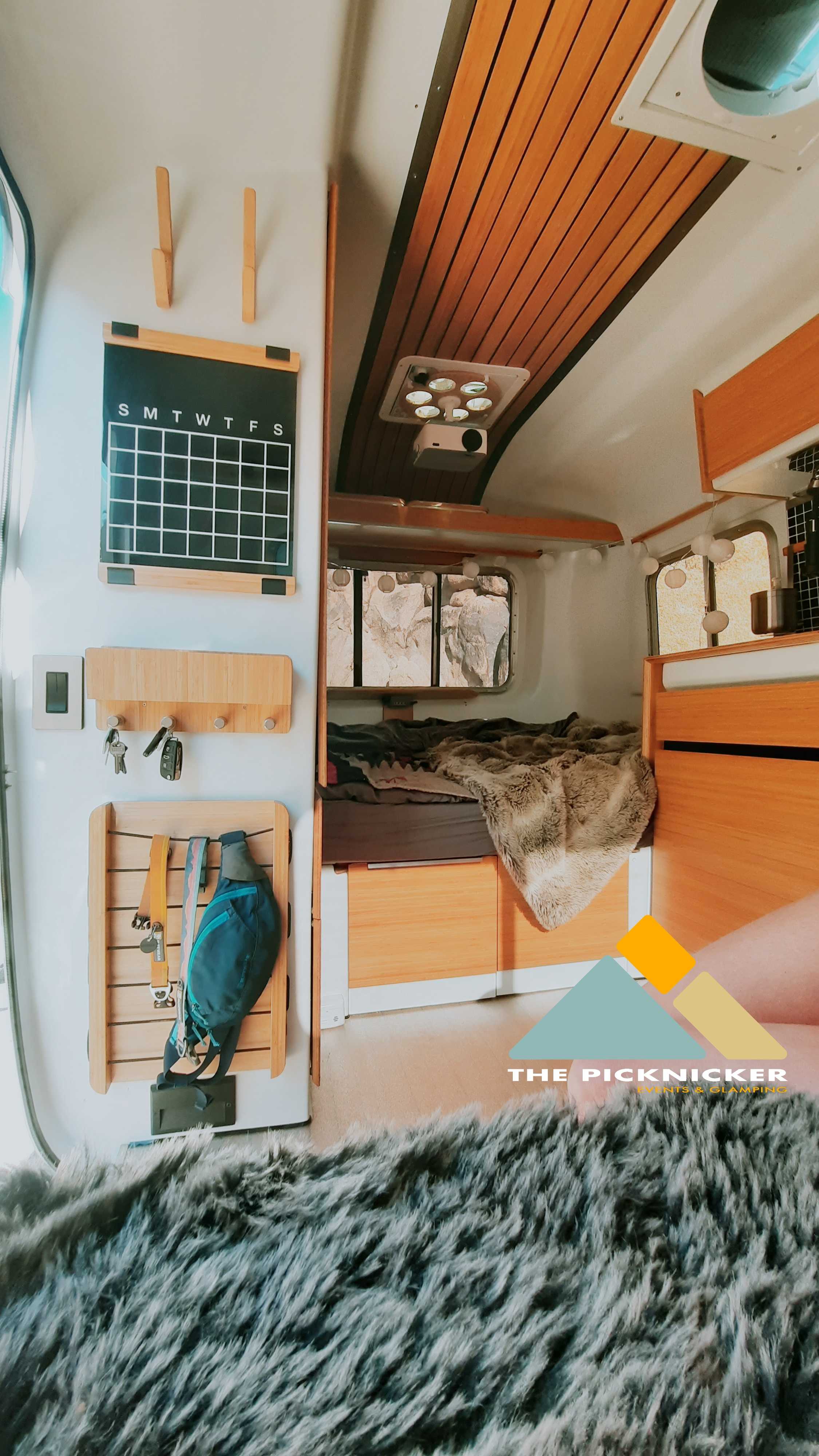 Cozy RV interior featuring a comfy bed, wall organizer, projector, and furry rug. Perfect for your next RV rental adventure!. Burro Vintage (OWNER TOWING ONLY) 1982