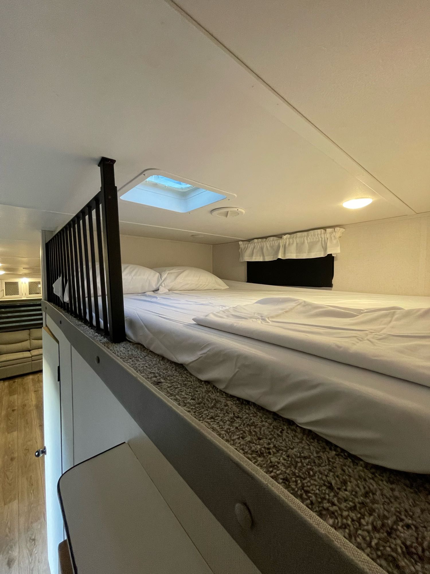 Comfortable loft bed in an RV rental, featuring white linens, a skylight, and a safety railing.. Forest River Prime time Crusader 382mbh 2022