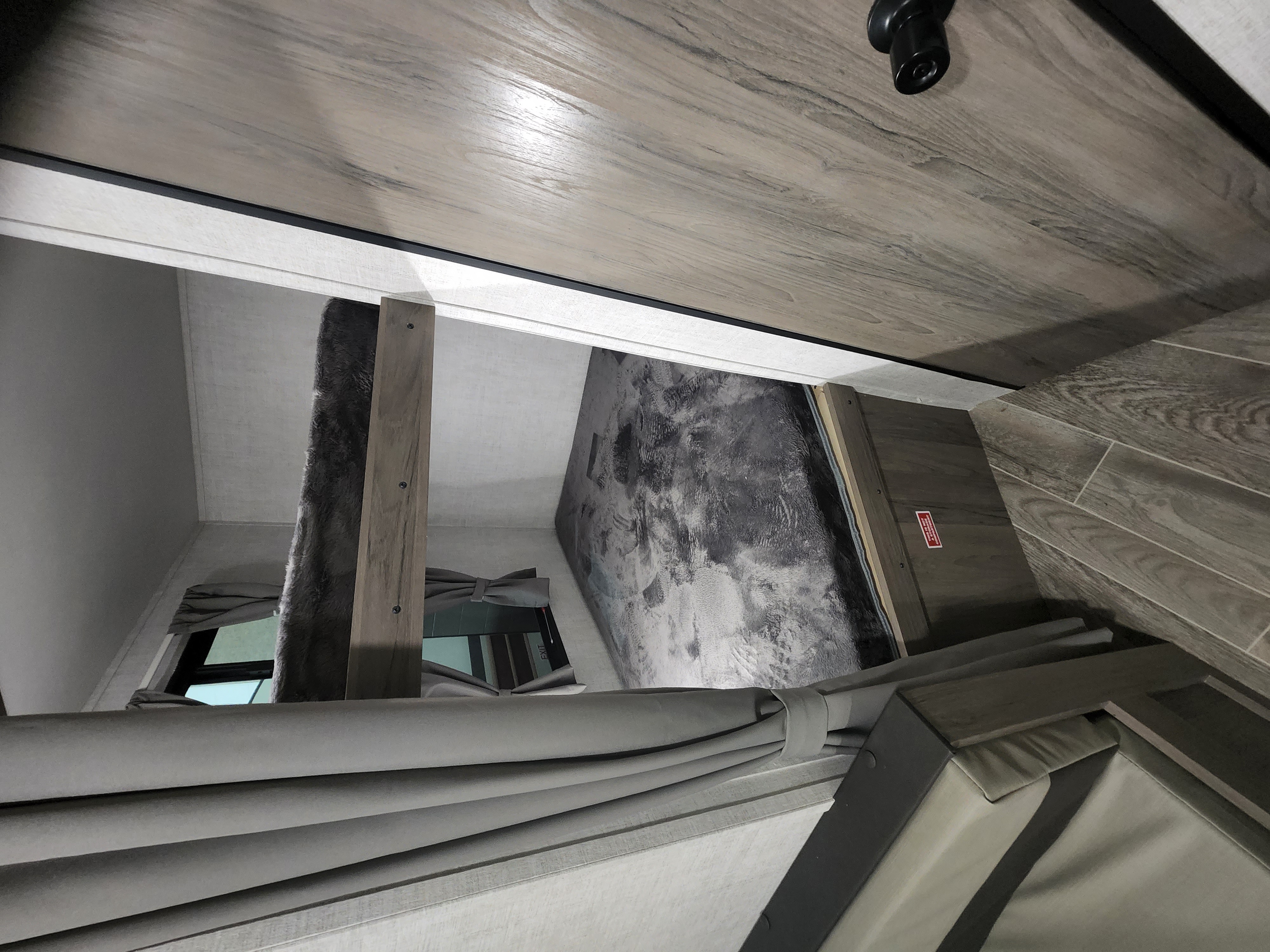 Inside an rv rental: A modern bunk bed area with gray soft furnishings, wood-look walls/ceiling, and a window.. Gulf Stream Ameri Lite 2022