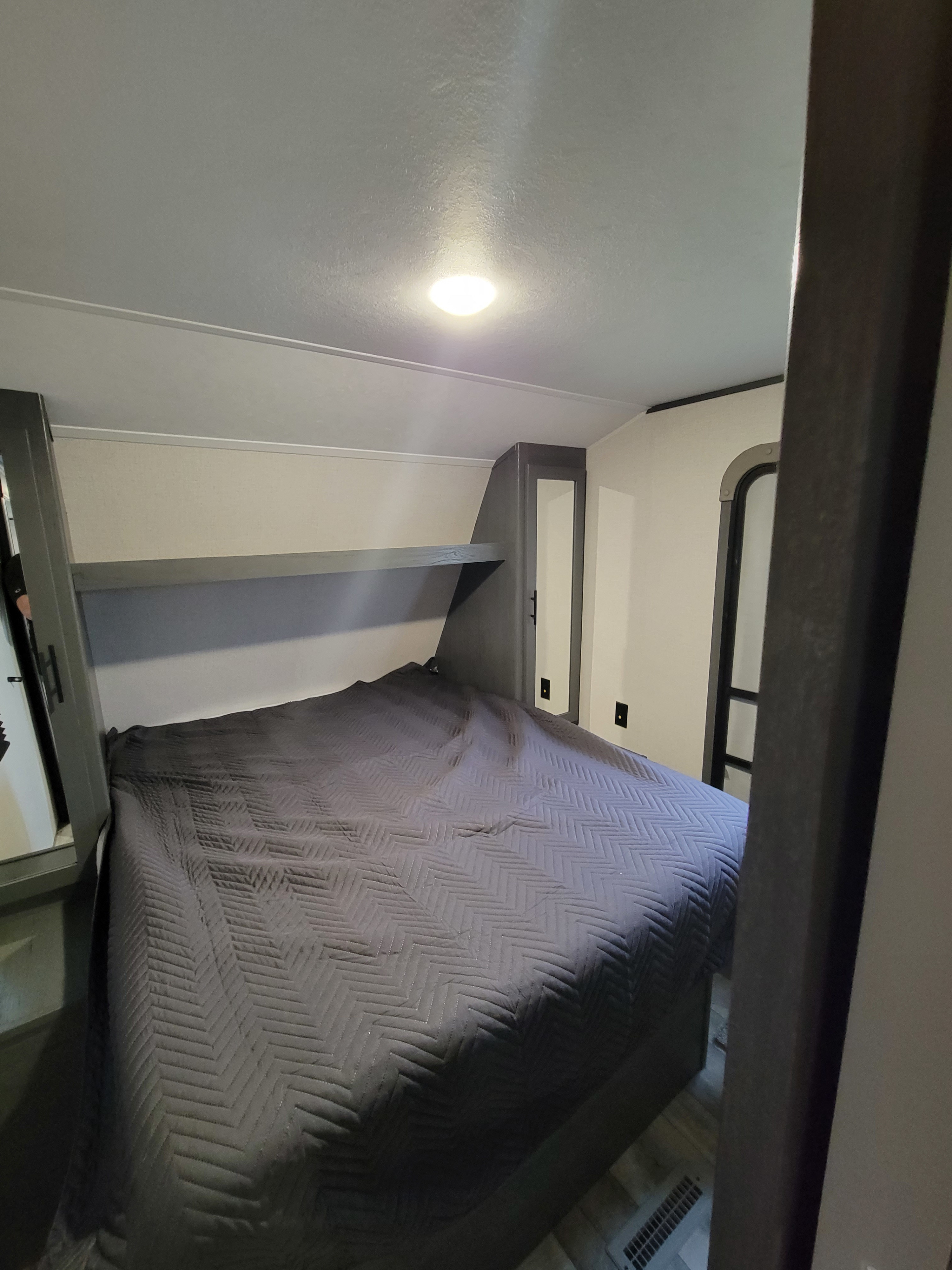 Cozy RV rental bedroom with a comfortable bed, an overhead shelf, and mirrored closet doors.. Dutchmen Other 2022