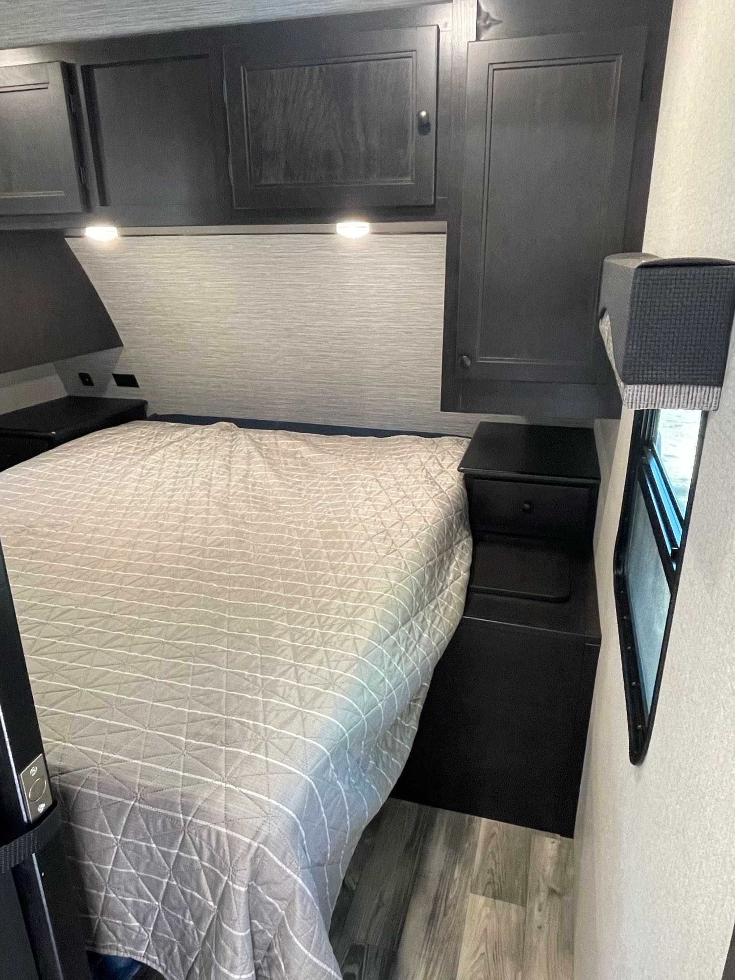 RV rental bedroom featuring a cozy quilted bed, dark overhead cabinets, and built-in nightstands. Perfect for travel.. Starcraft Superlite 261BH 2022