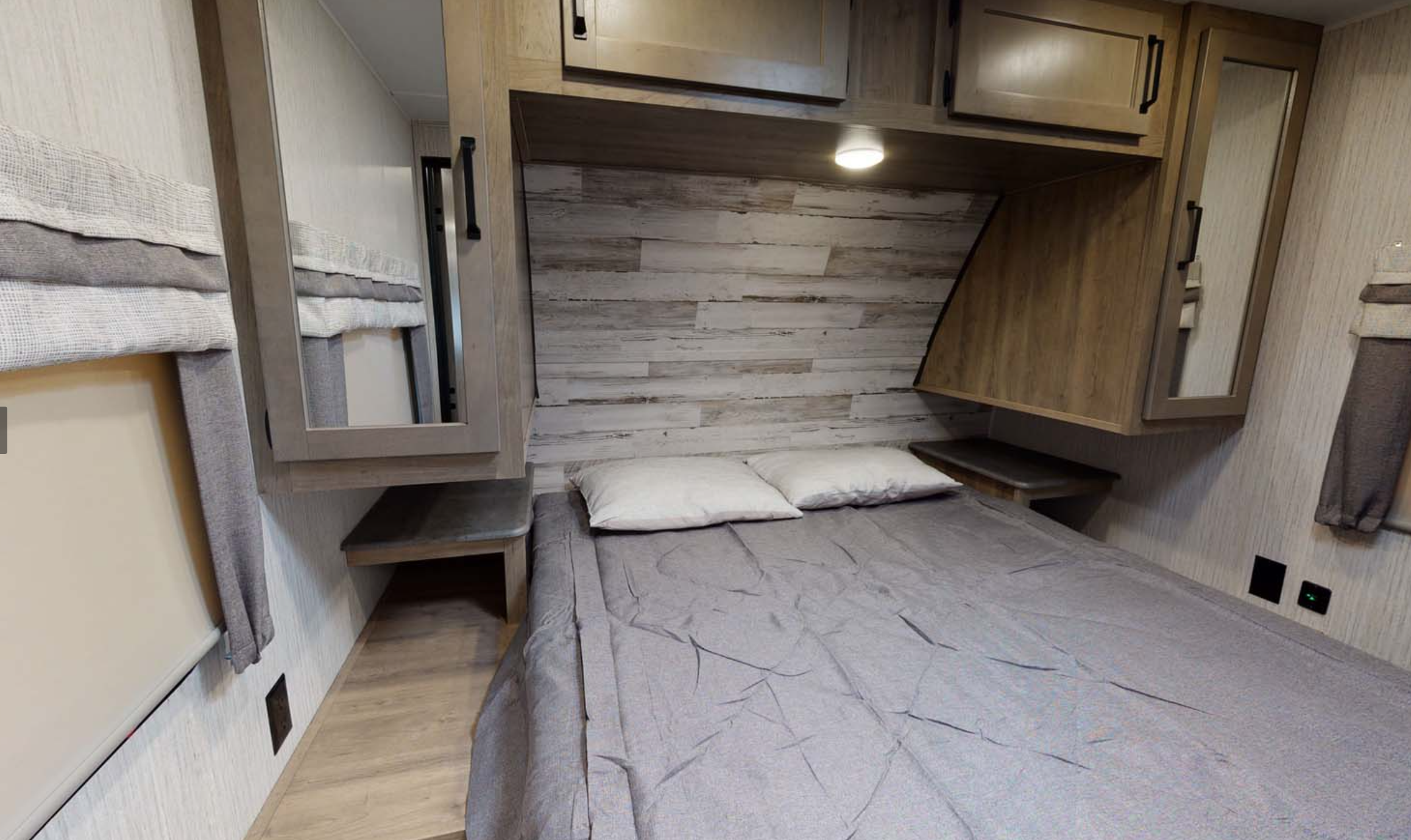 Cozy RV rental bedroom with a bed, wood paneling, overhead cabinets, and side mirrors. Perfect for your trip.. PUMA 28BHSS 2022