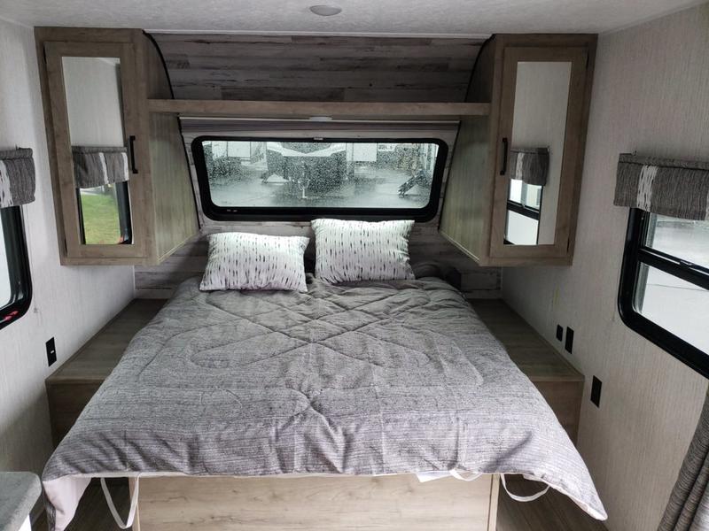Step into comfort with this modern RV rental bedroom featuring a cozy bed, ample storage, and large windows.. Forest River Palomino Puma XLE Lite 2021