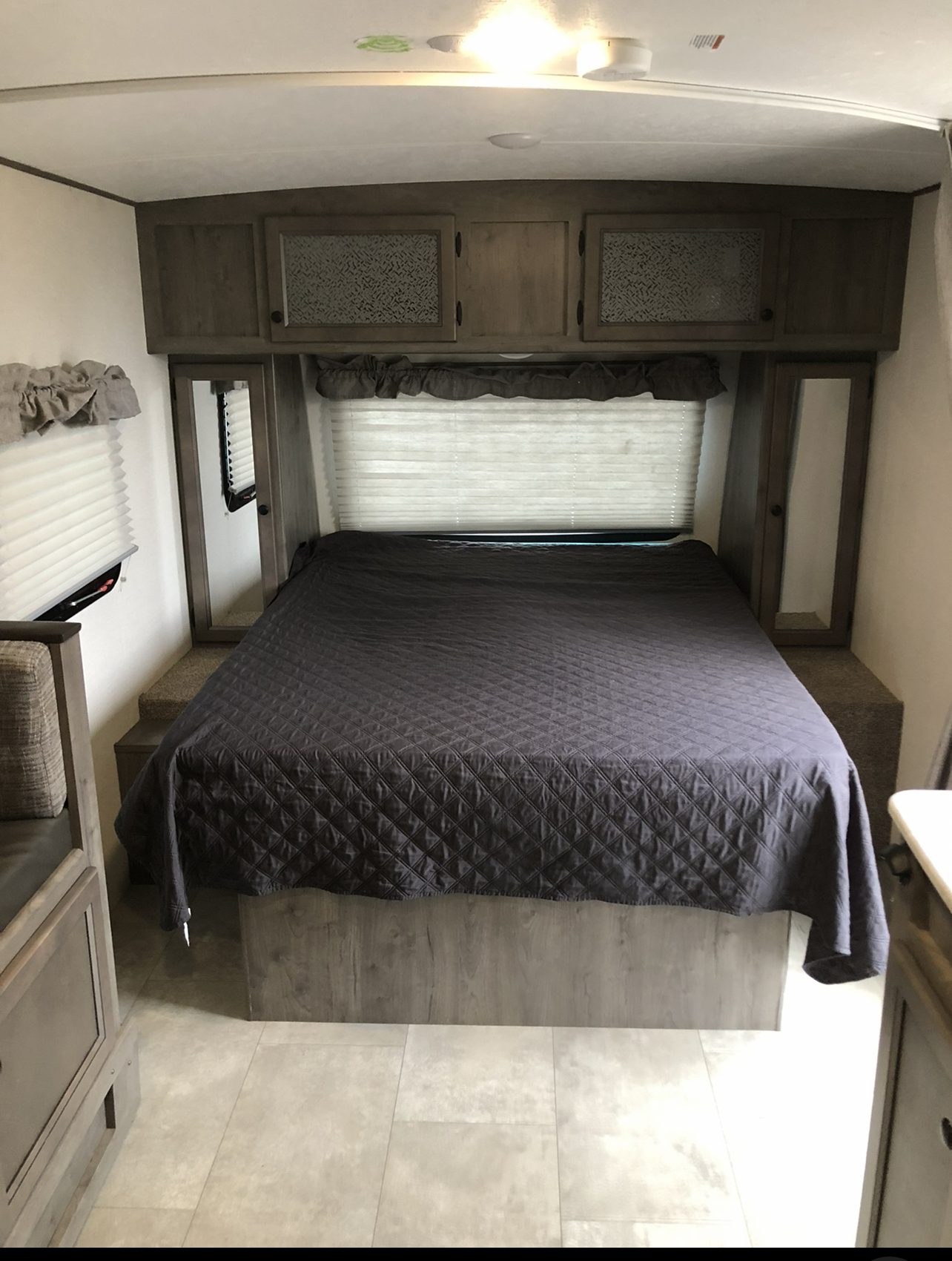 Cozy RV rental bedroom with queen bed, ample storage cabinets, and window shades. Ideal for your next travel adventure.. Forest River apex 2020