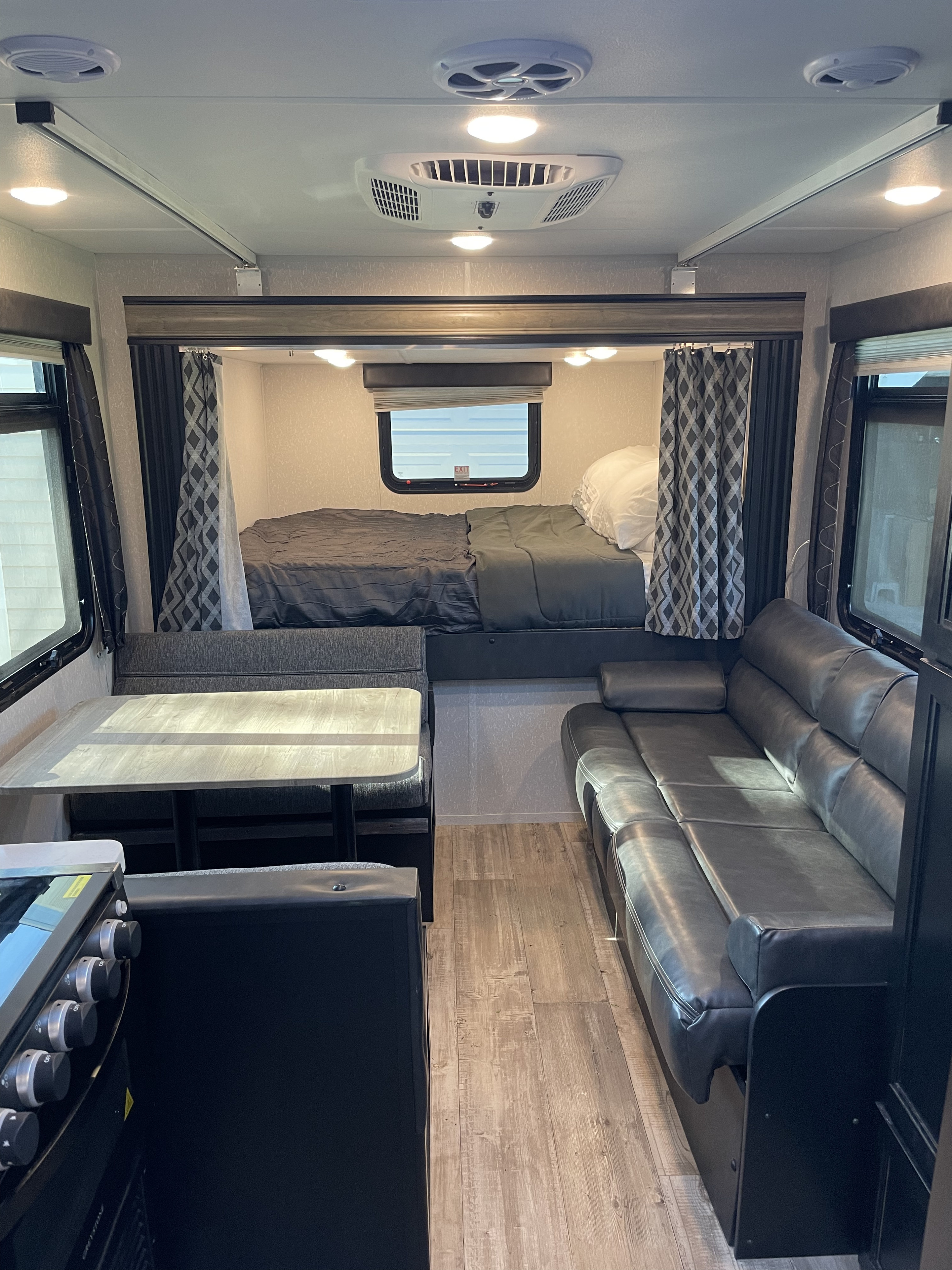 Bright RV rental interior featuring a cozy bed, comfortable dinette, and relaxing sofa area.. Forest River Cherokee Grey Wolf 2021