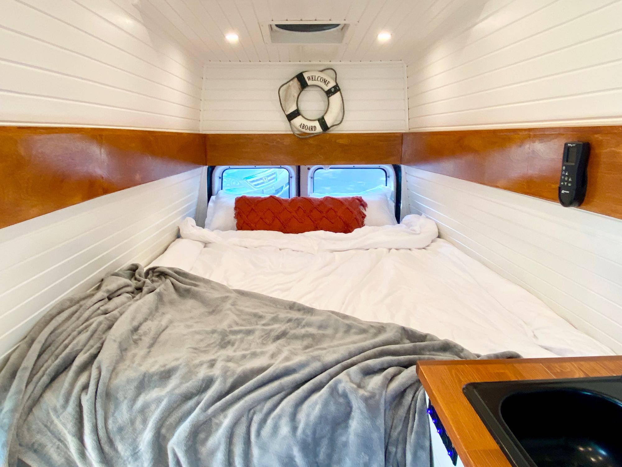 RV rental: Cozy camper van bedroom with comfortable bed, white plank walls, and nautical decor.. Ford Ford E350 2014
