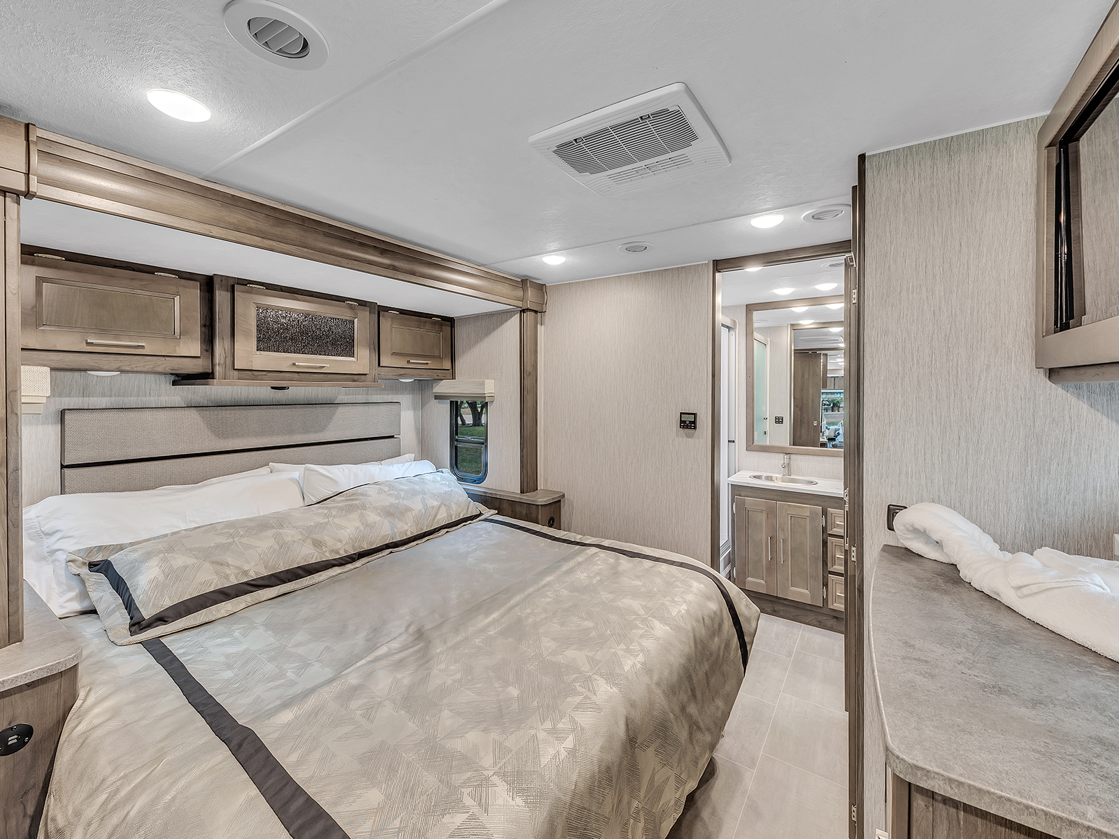 Experience comfort in this RV rental's modern bedroom. Features a large bed, cabinets, and a private bathroom.. Coachmen Mirada 2021
