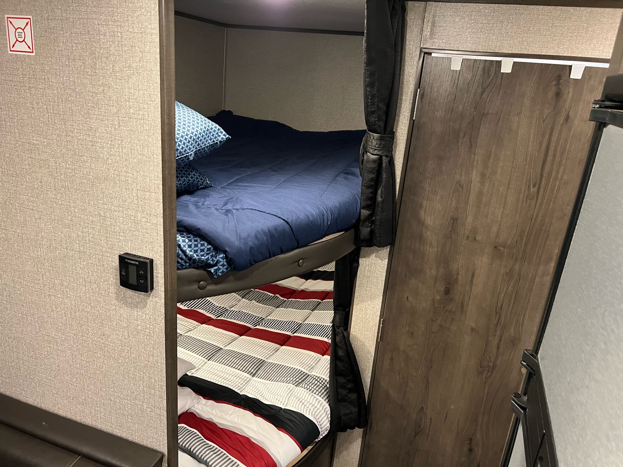 Inside an RV rental: comfortable bunk beds with blue and striped bedding. Perfect for family trips in a cozy mobile sleeping area.. Jayco Jay Flight 2021