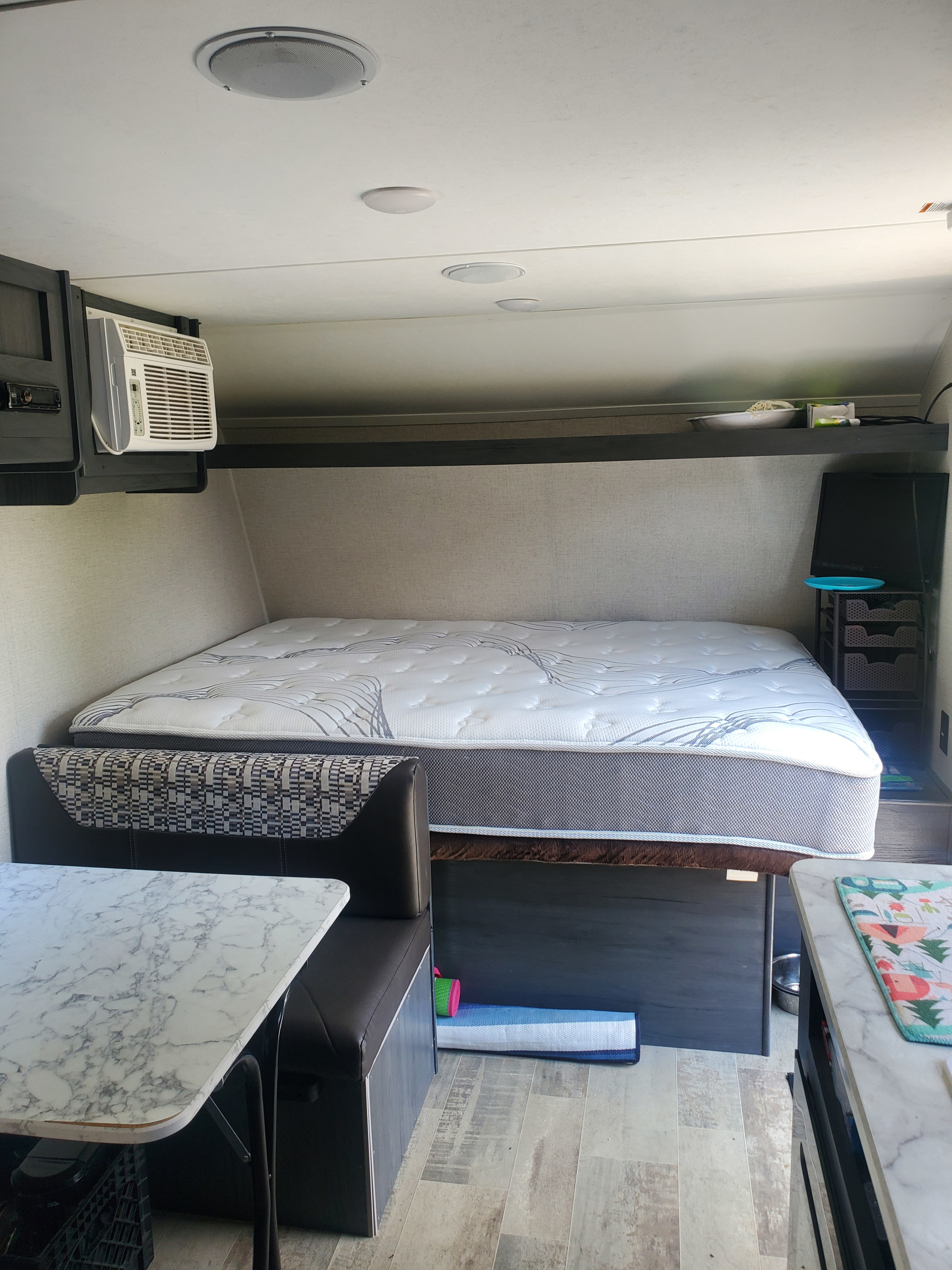RV rental interior: comfortable bed, dinette with marble-look table, and AC unit. Enjoy a pleasant camping trip!. Aspen Trail LE 2021