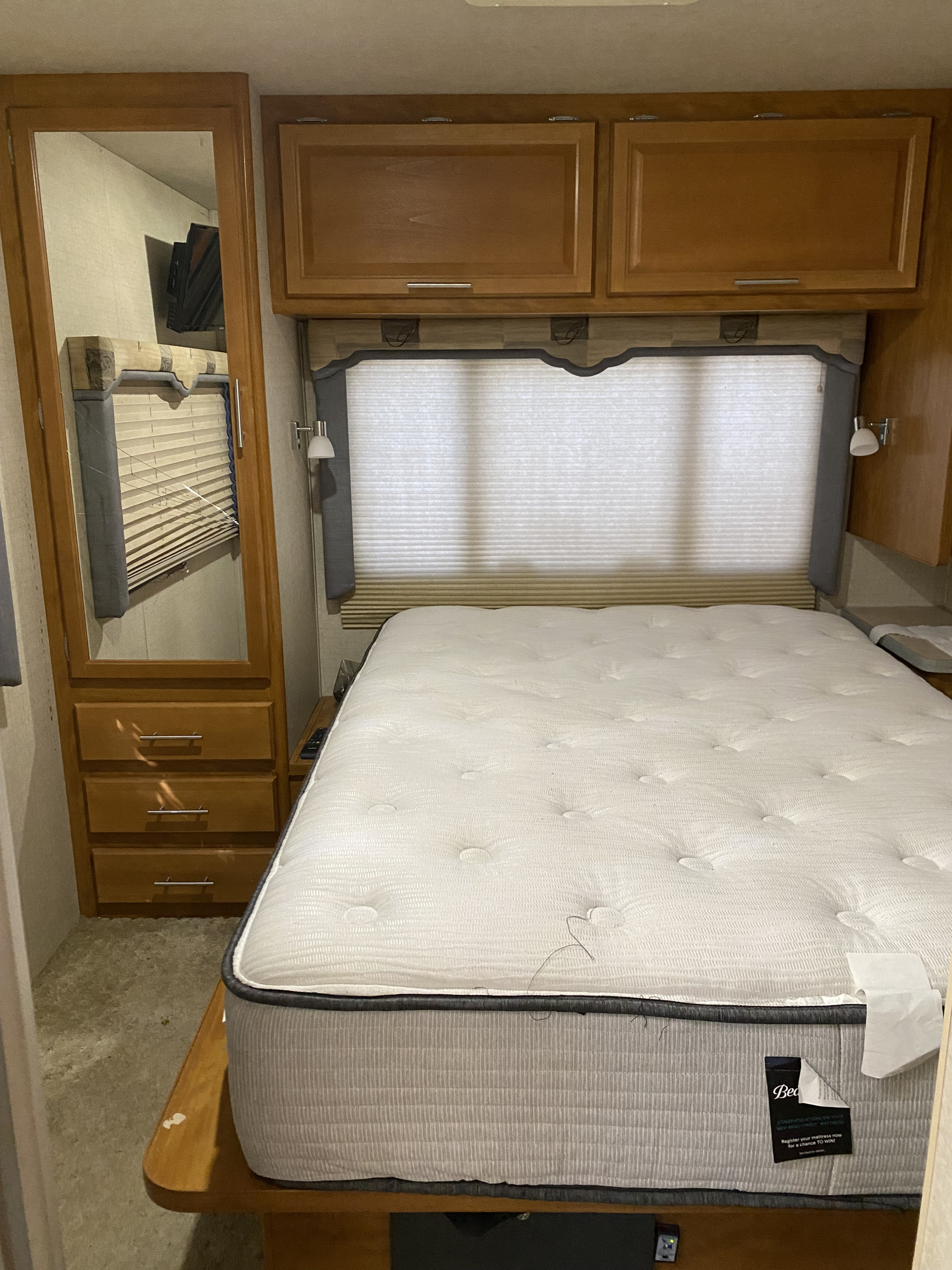Cozy RV rental bedroom featuring a new mattress, built-in storage, and window blinds for comfortable travel.. Tioga Tioga Motorhome 2004