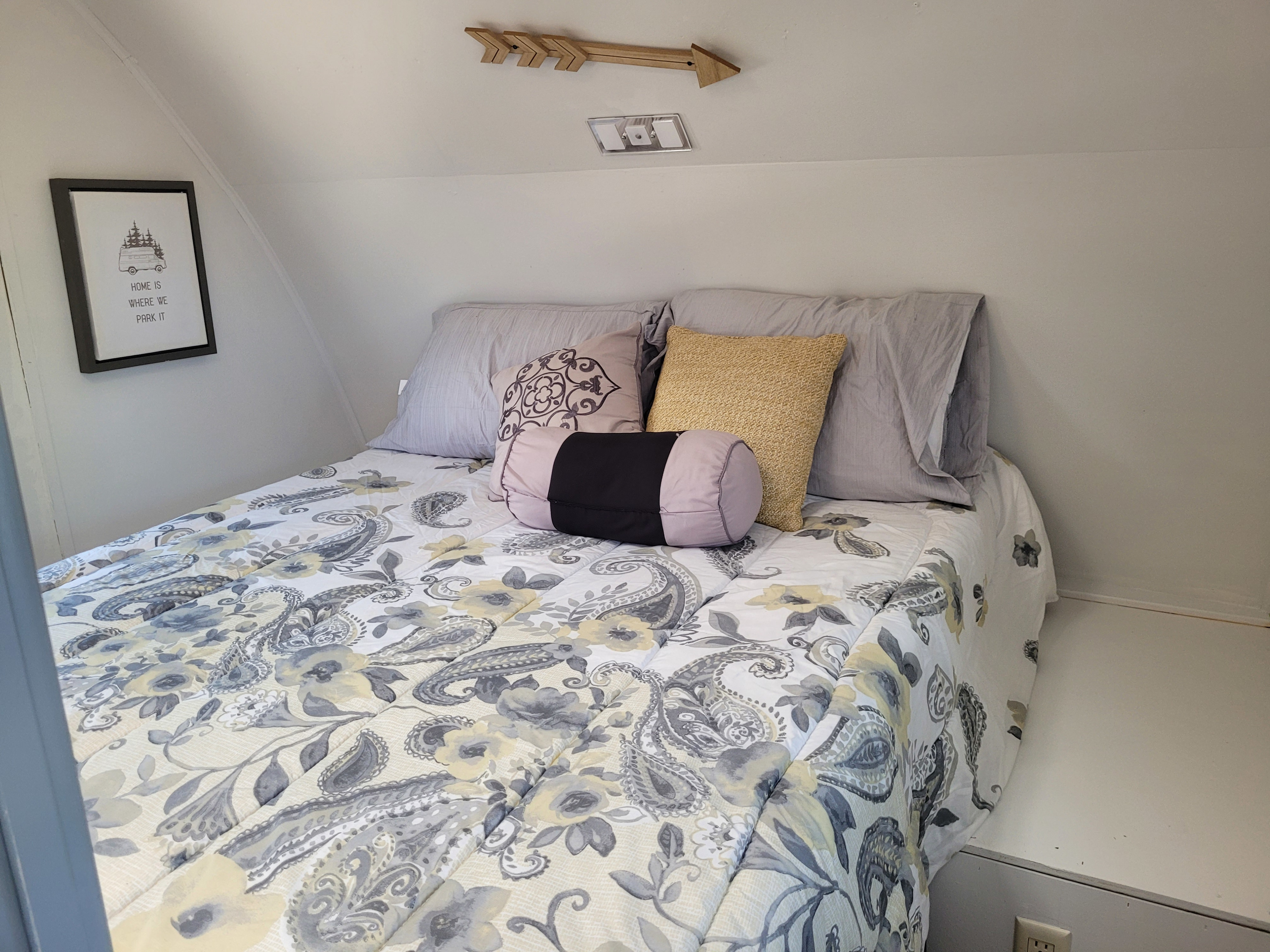 Enjoy a cozy night in this RV rental's clever bedroom, featuring floral bedding and a camper art print.. Keystone RV Passport Ultra Lite 2009