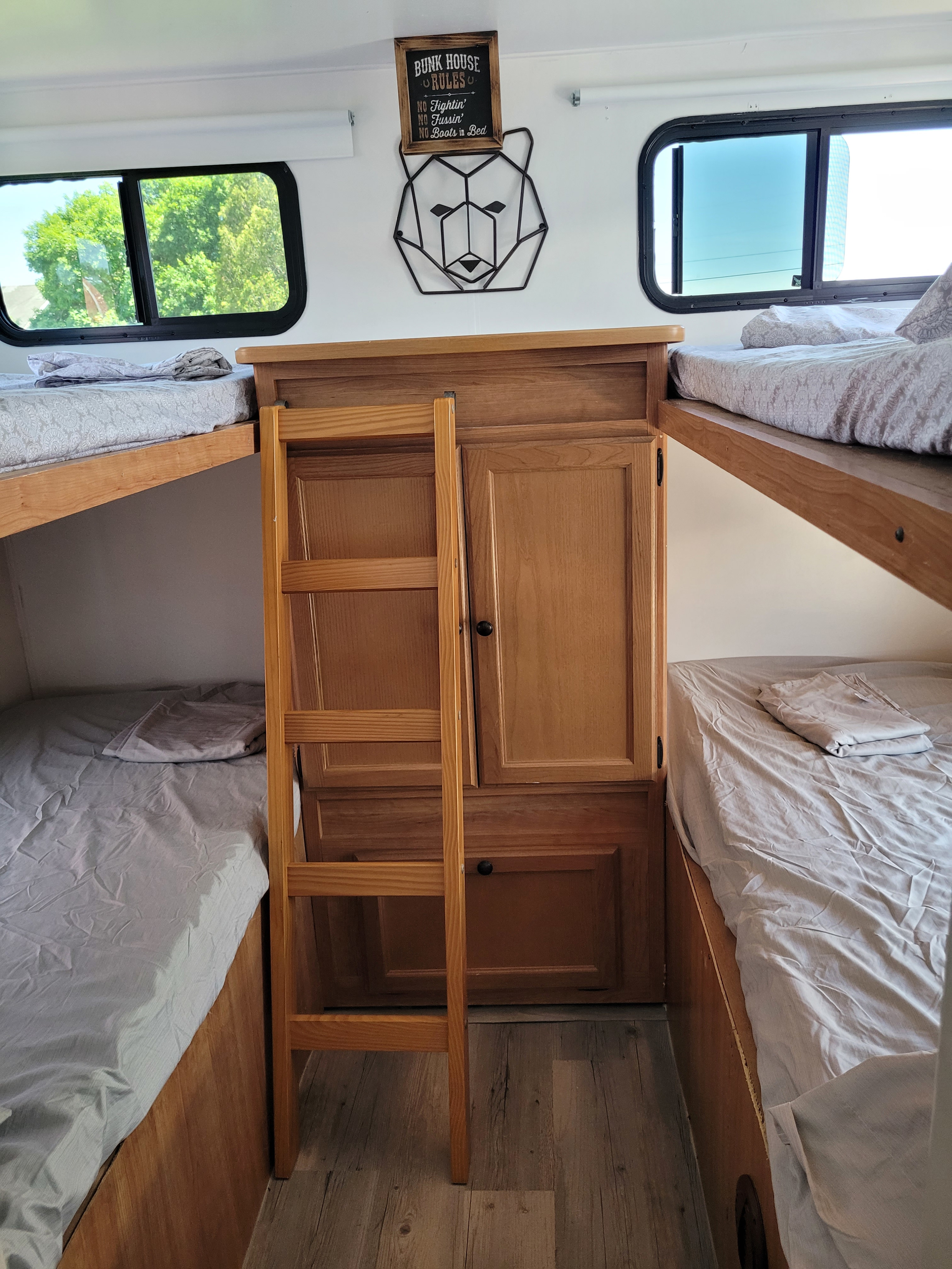 Inside an RV rental, a compact "bunk house" with four beds, a central wardrobe, and playful bear-themed decor.. Keystone RV Passport Ultra Lite 2009