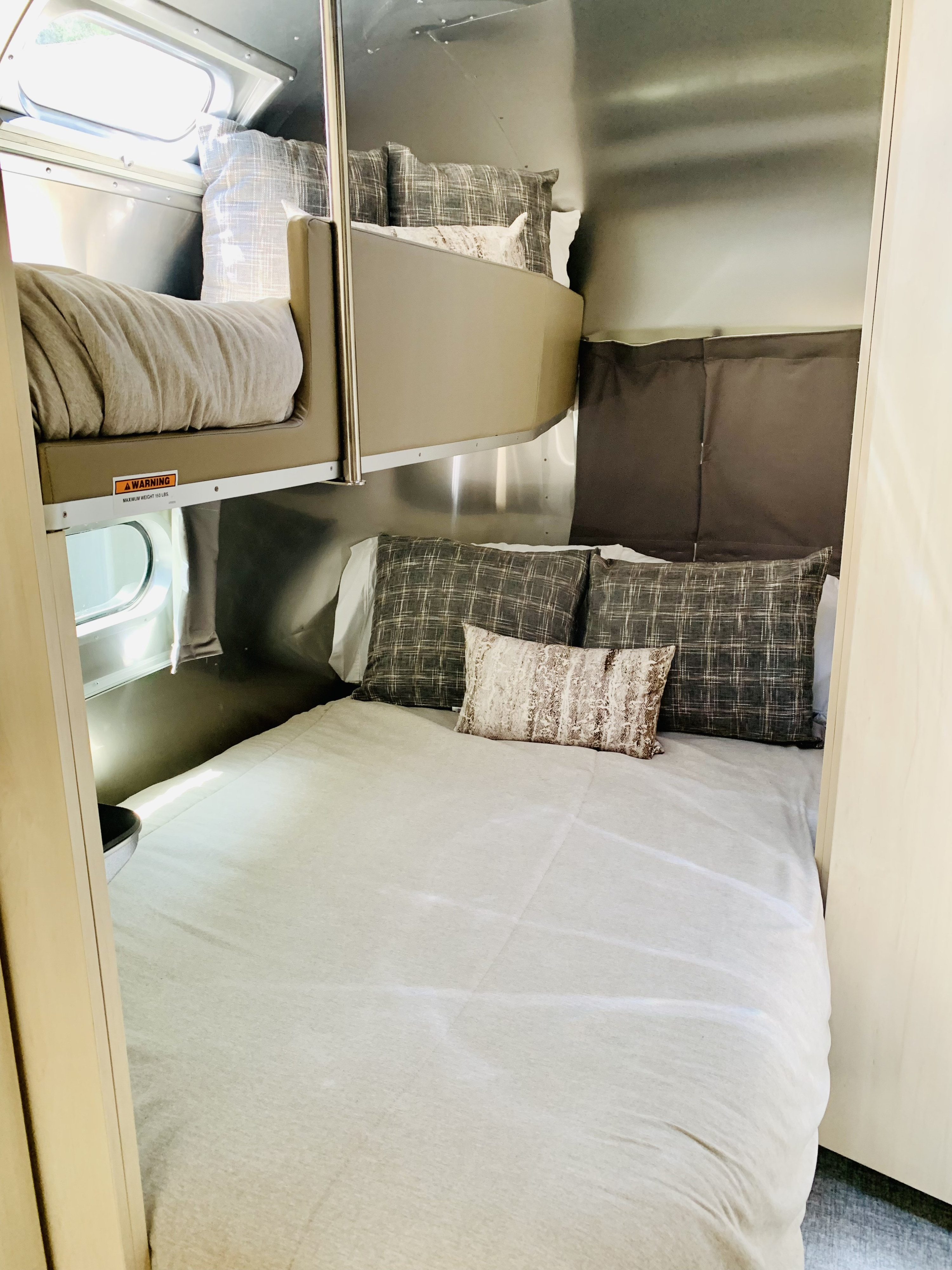 Cozy RV rental bedroom with a comfy main bed and an upper bunk bed, featuring a classic Airstream interior design.. Airstream Flying Cloud 2022