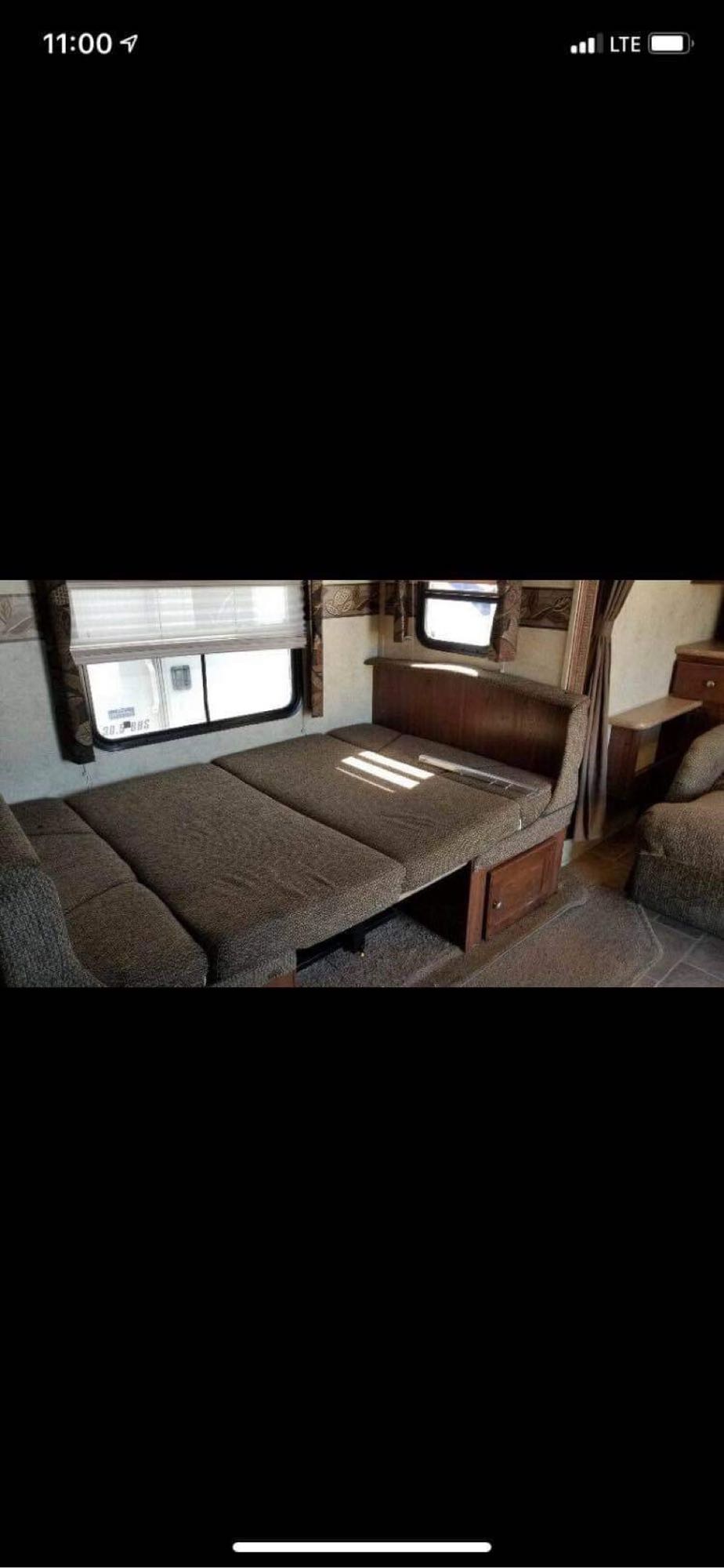 RV rental interior showing a brown fabric sofa that converts into a bed, with windows, perfect for comfortable travel.. Forest River Flagstaff Super Lite 2012