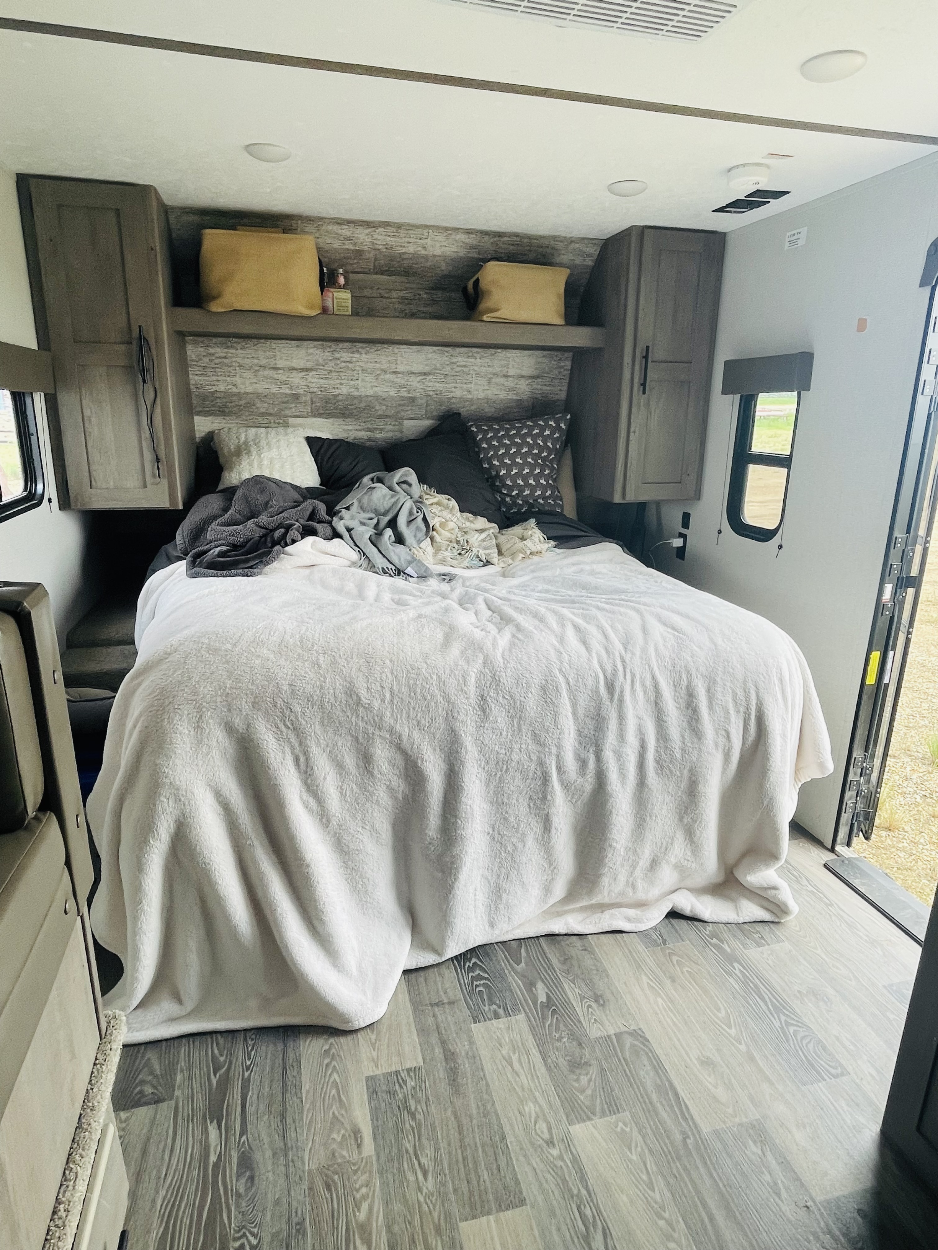 Spacious RV rental bedroom featuring a cozy bed, ample overhead storage, and light wood-look flooring.. Keystone RV Springdale 2021