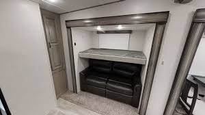 This RV rental's bunk room features a comfy top bunk above a versatile reclining sofa, offering extra sleeping space.. Coachmen Chaparral 2021