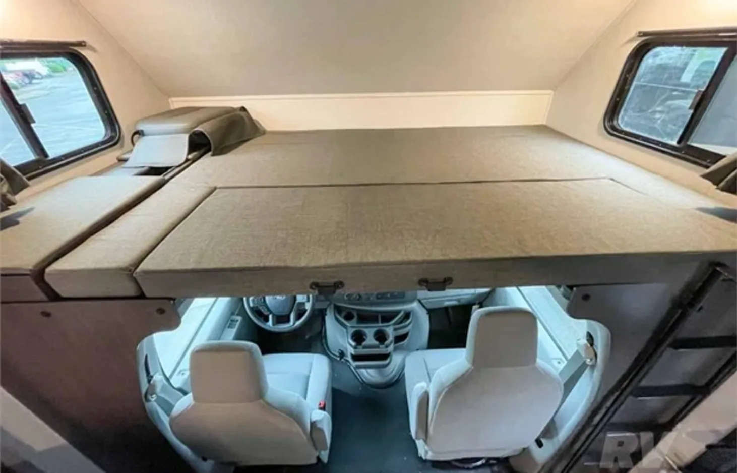 Inside an RV rental: a comfortable over-cab sleeping area viewed from above, overlooking the driver's cockpit.. Forest River Solera 2022