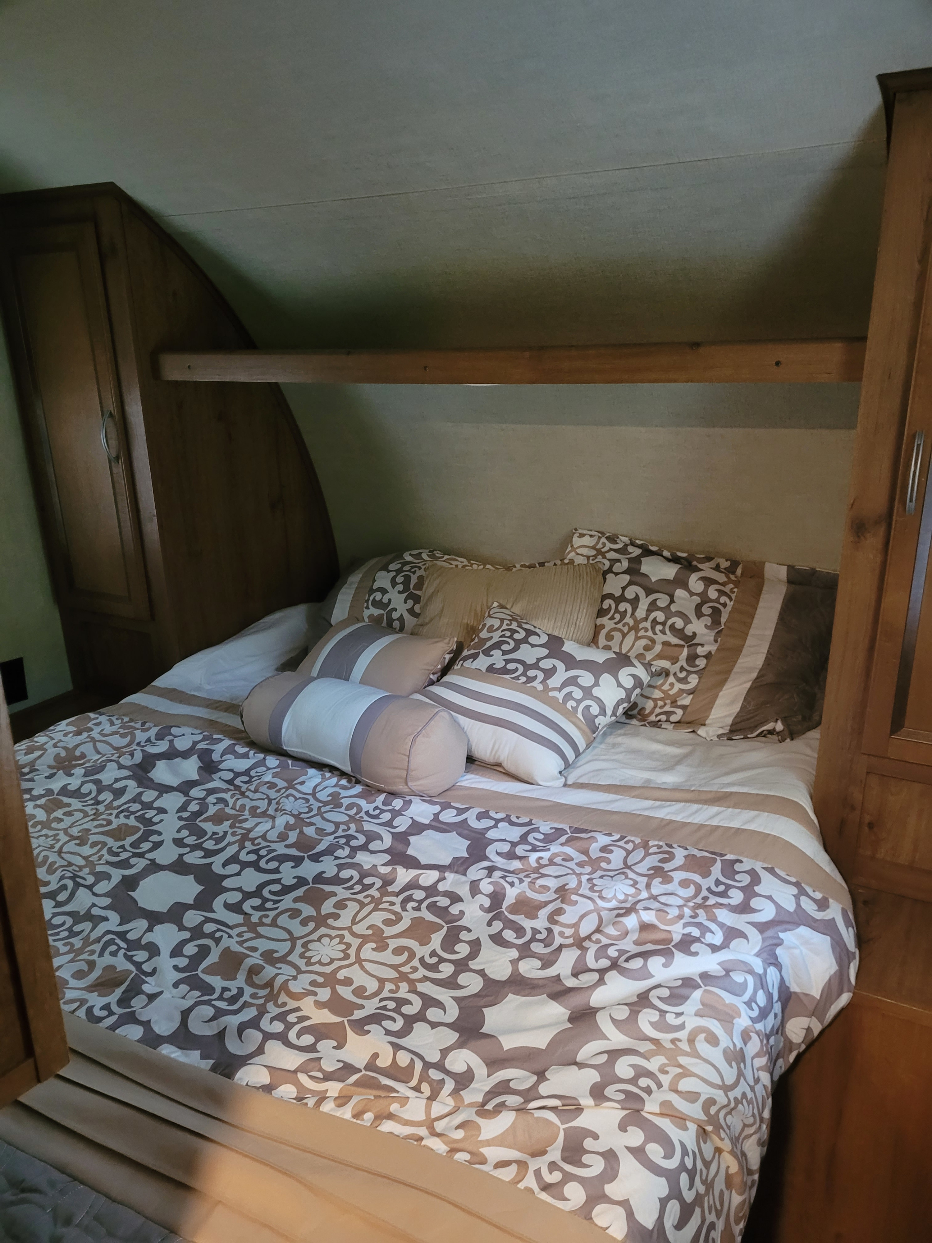 This RV rental features a comfortable bedroom with patterned bedding, pillows, and built-in wooden storage.. Gulf Stream Ameri-Lite 2017