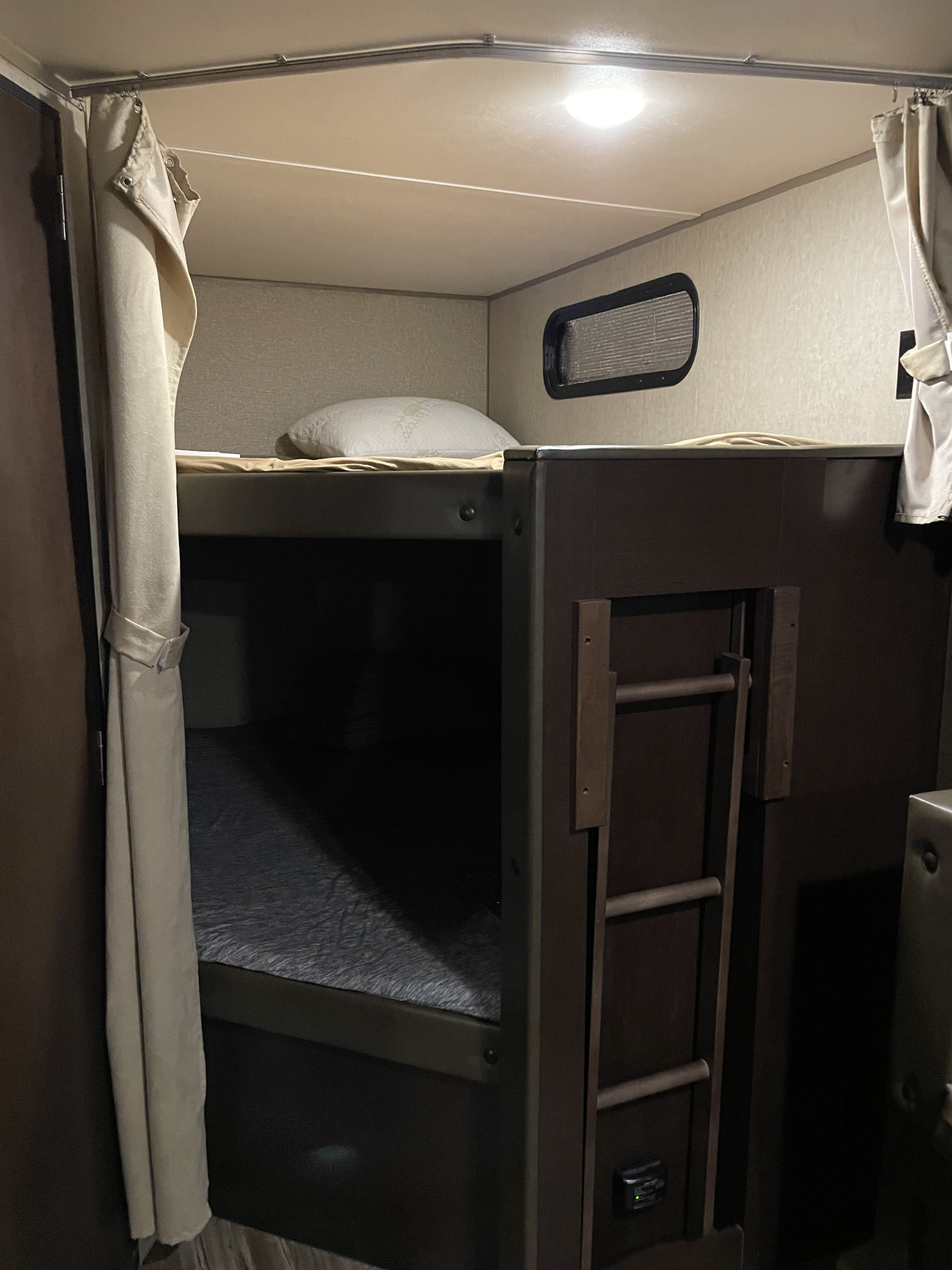 Cozy rv rental interior with bunk beds, ideal for family trips. Features include window, curtains, and ladder.. Forest River Cherokee Grey Wolf 2016