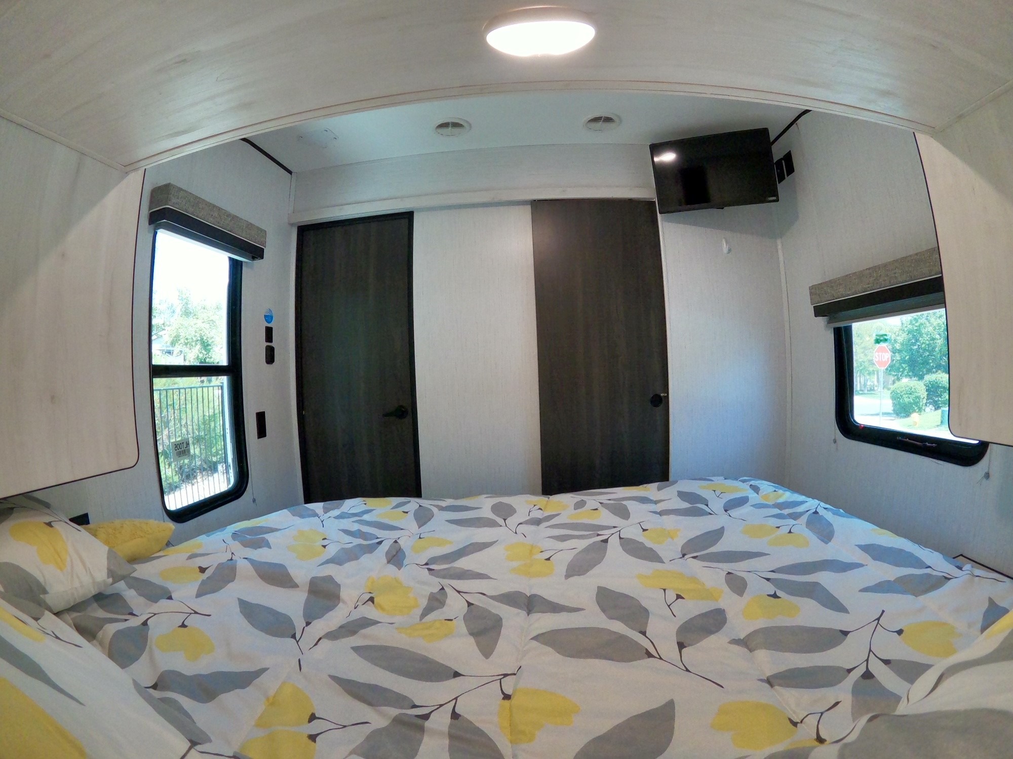 Inside a comfortable RV rental bedroom, featuring a vibrant floral bed, dual windows, and TV. Ideal for travel.. Heartland Lithium 2414 2021