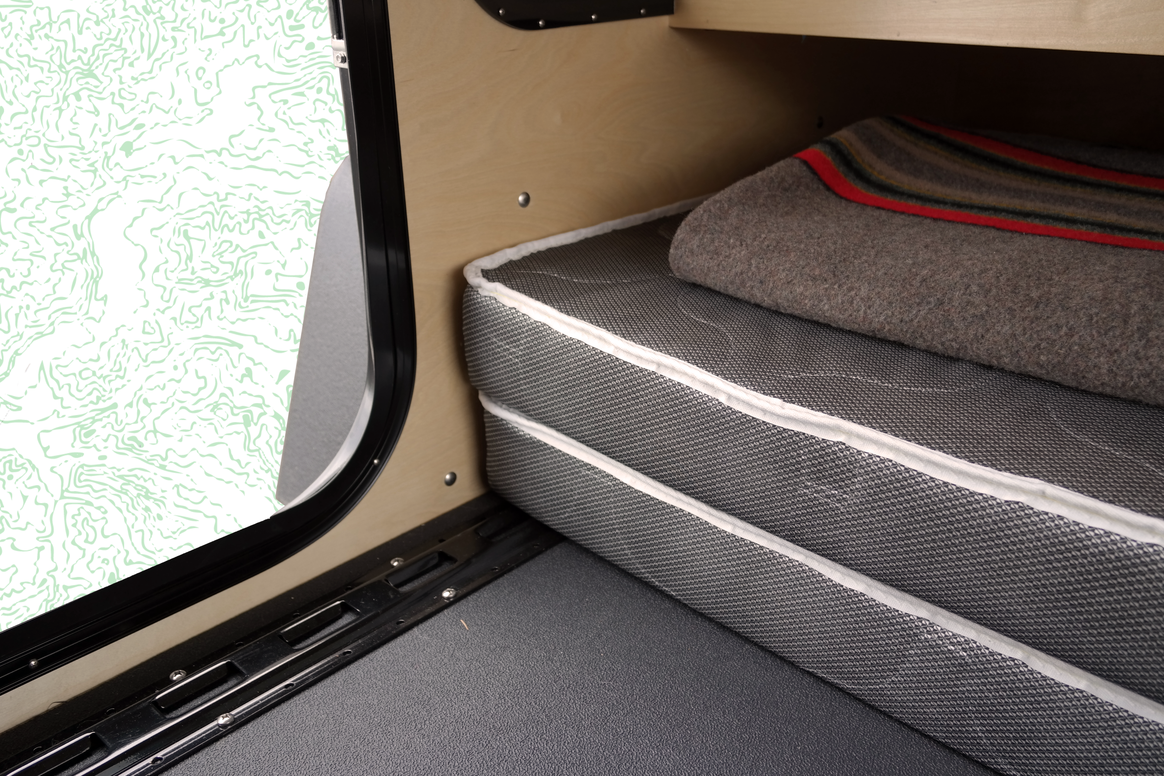 RV rental sleeping area showing a comfortable mattress, cozy blanket, and a unique window design, ideal for camping.. Oregon Trail'R DoDrop ALPHA 2021