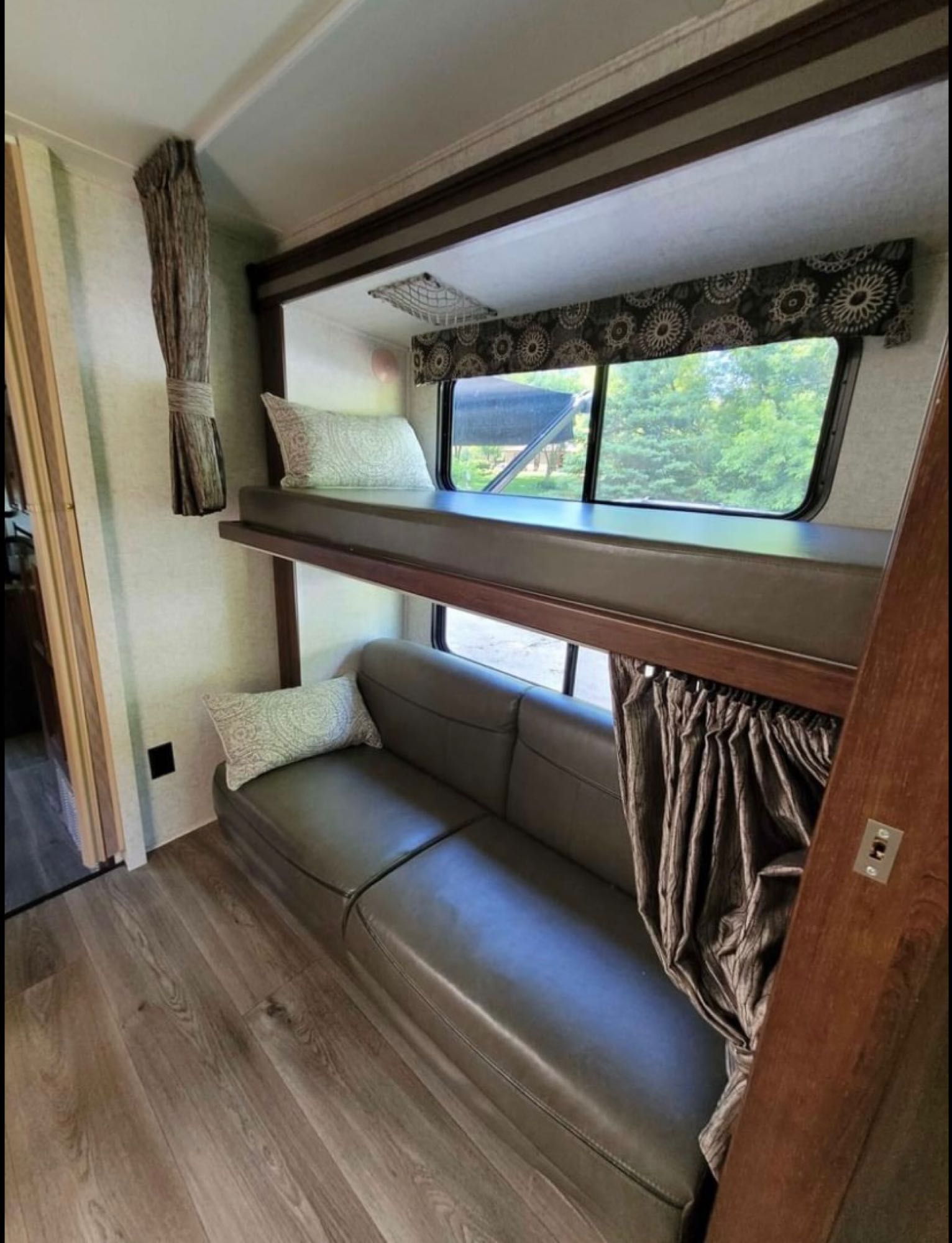 RV rental interior showing bunk beds, a sofa, and wood flooring. A cozy, functional living space for travel.. Forest River Sunseeker 2017