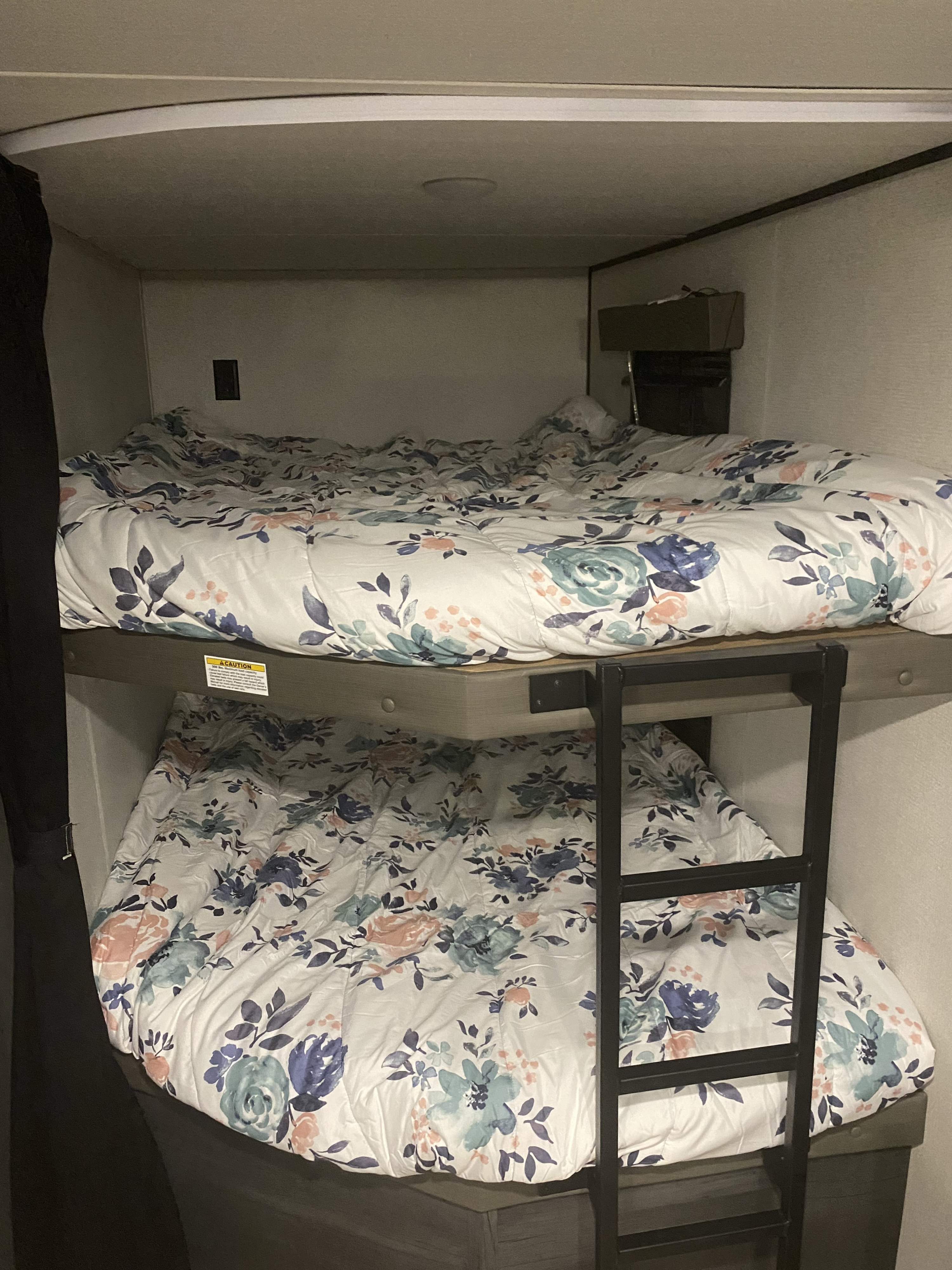 RV rental sleeping area: Twin bunk beds with matching floral comforters, offering cozy lodging.. Keystone Hideout 2022