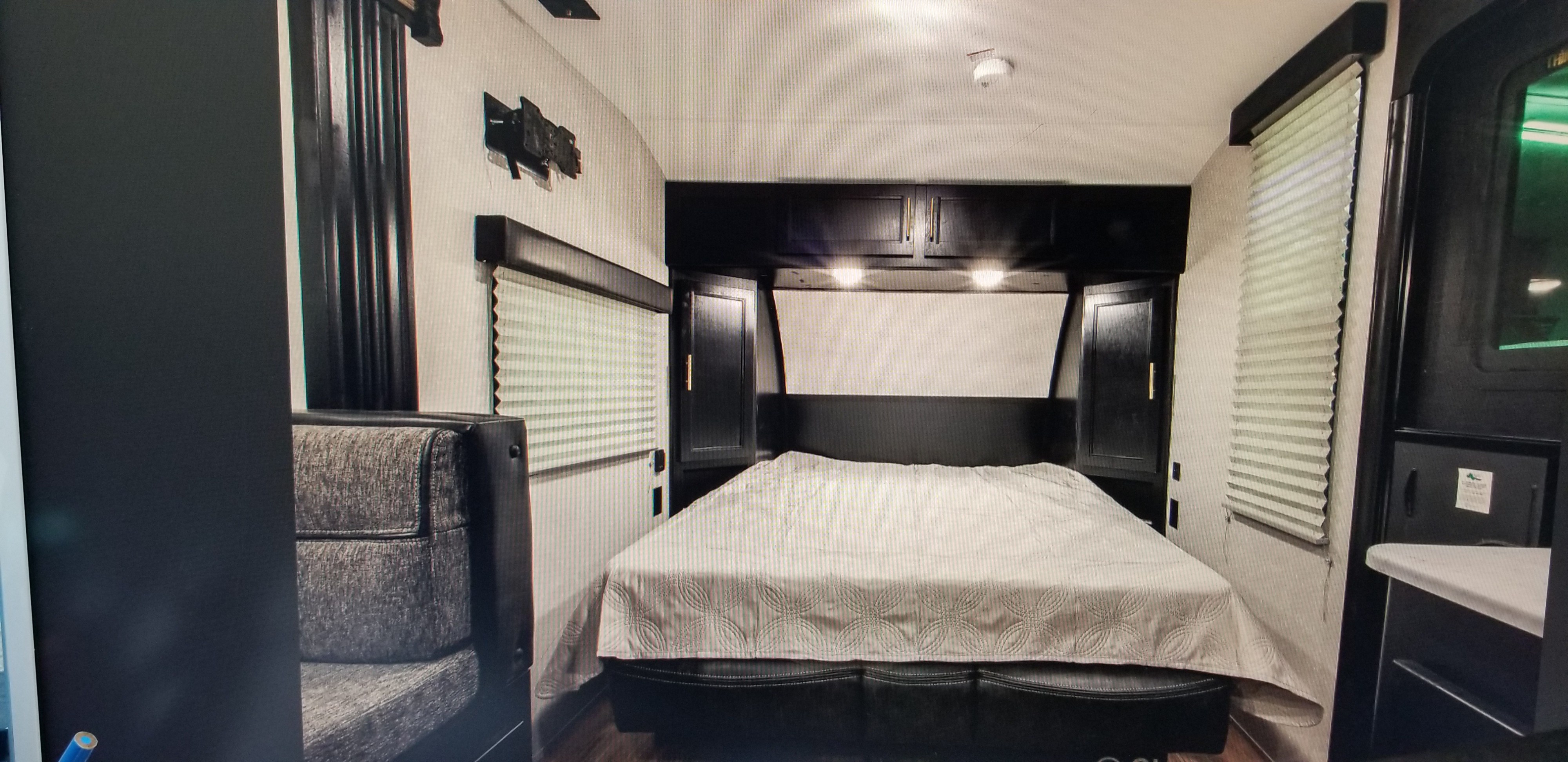 Comfortable RV rental bedroom featuring a full bed, overhead storage cabinets, and privacy blinds for a cozy travel experience.. Forest River Cherokee 2022
