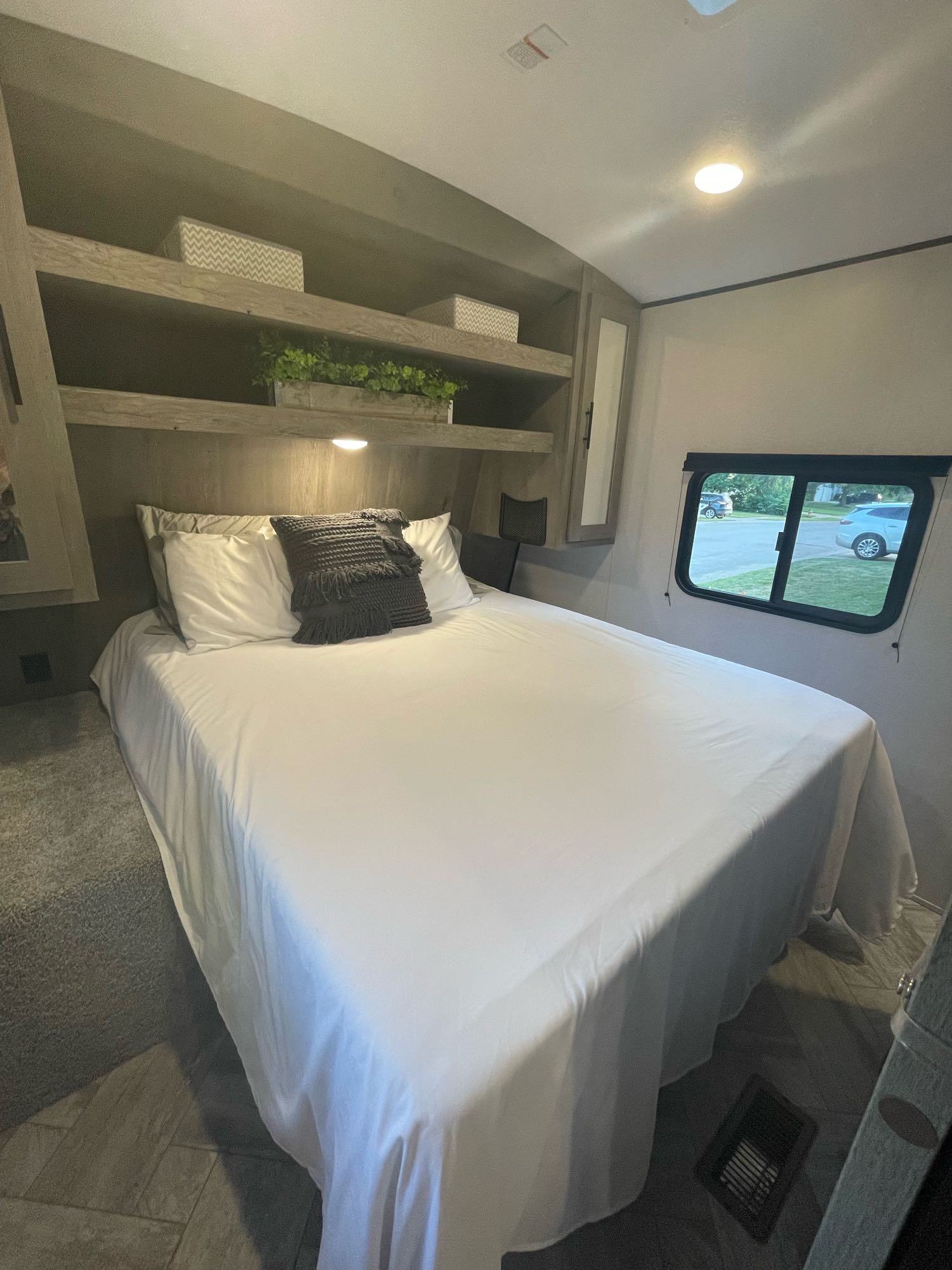 Bright RV rental bedroom: comfy bed, storage shelves, & window view. Your cozy retreat on wheels.. Keystone RV Springdale 2021
