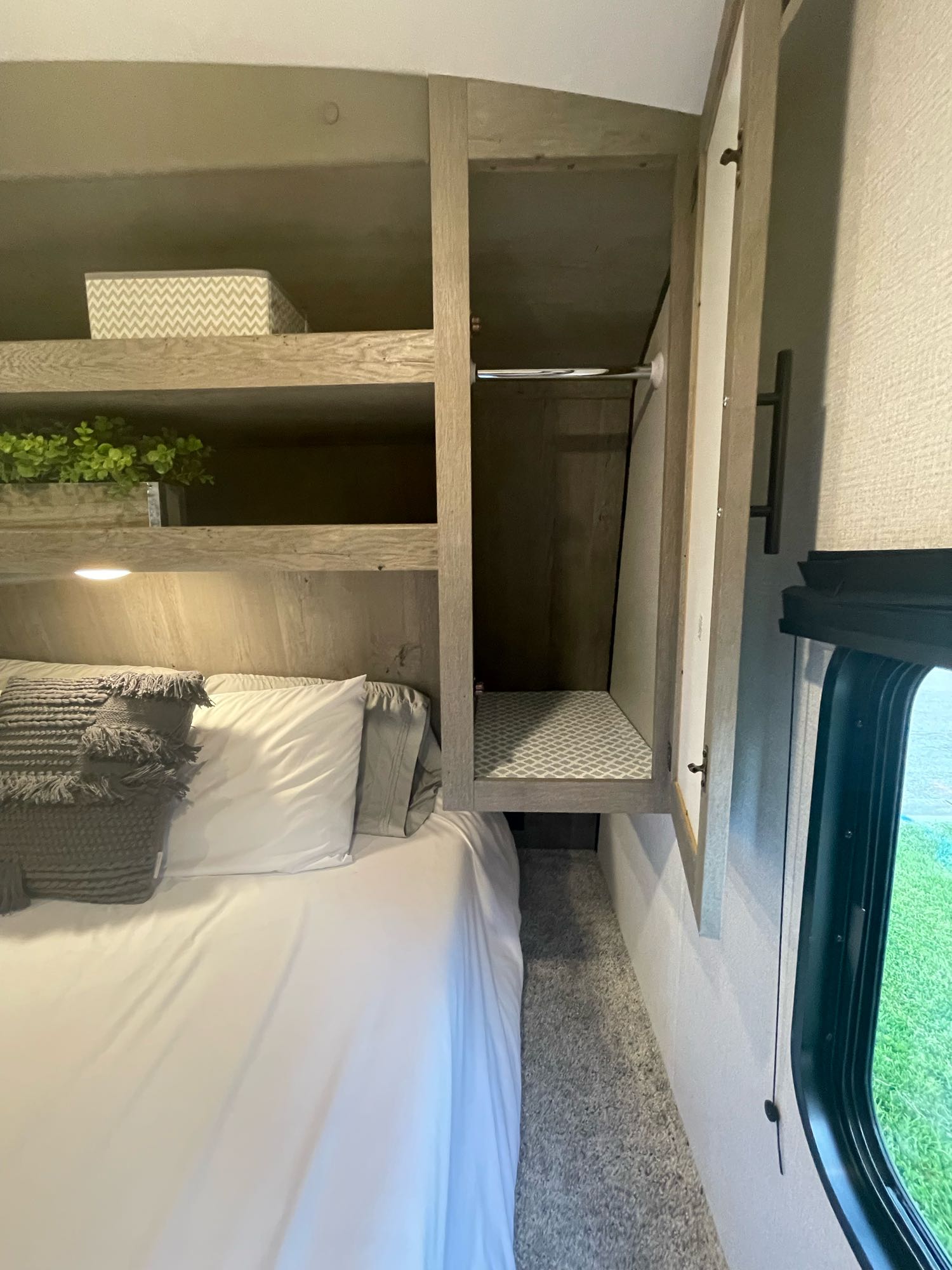 Inside an RV rental: a compact bedroom featuring a comfortable bed, shelves, and a closet with a hanging rod.. Keystone RV Springdale 2021