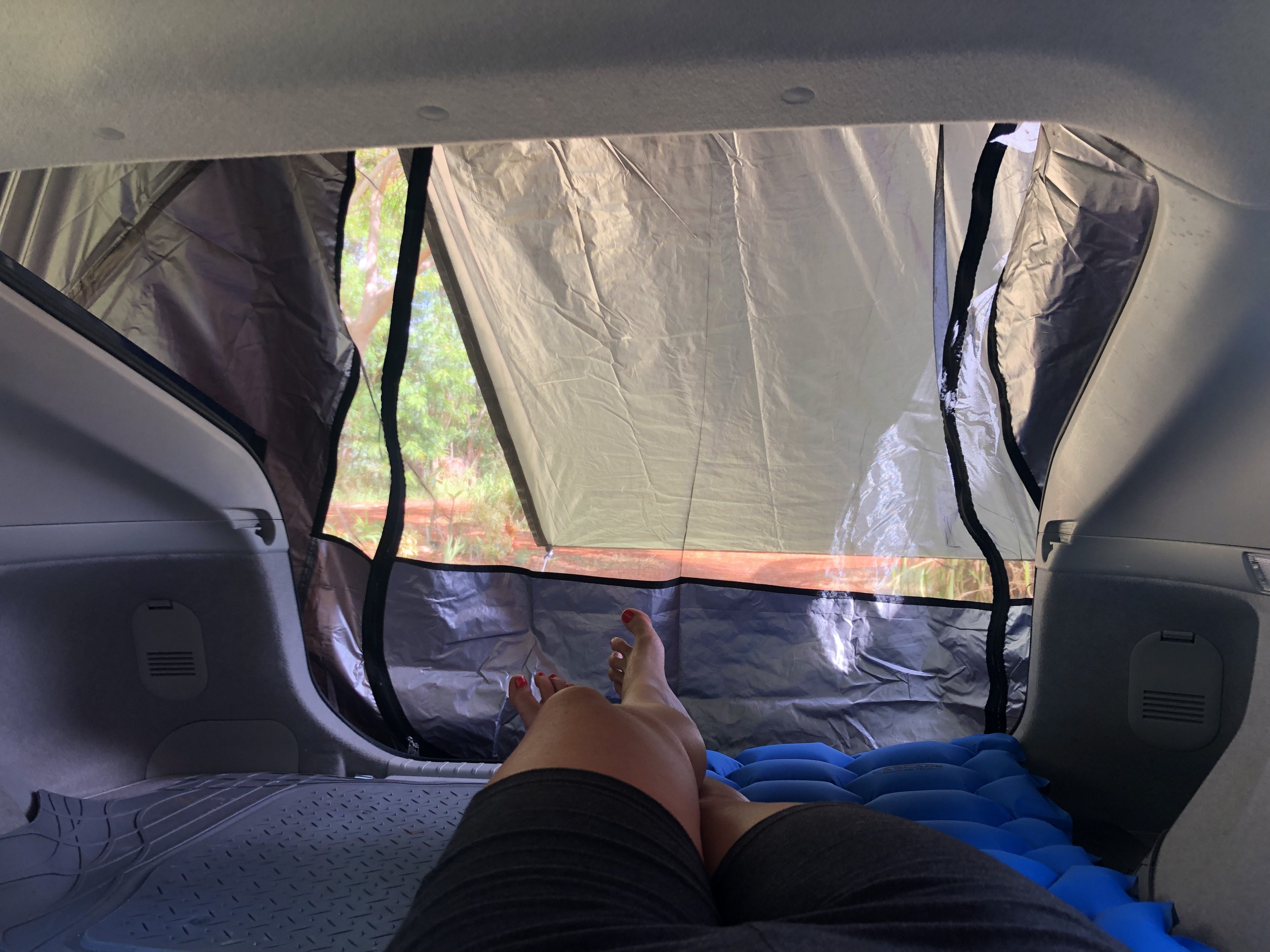Relaxing inside a car with a setup for camping: blue sleeping pad & attached tent. Perfect for an RV rental alternative road trip.. Custom Camper 2010