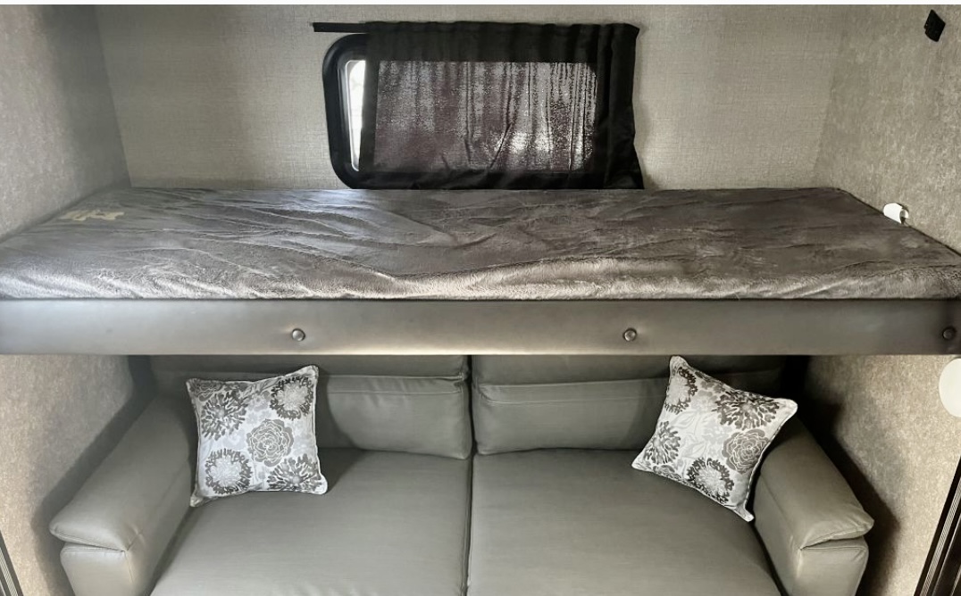 RV rental: Comfortable interior featuring a bunk bed over a sofa with pillows, providing versatile sleeping space.. Jayco Eagle HT 2020