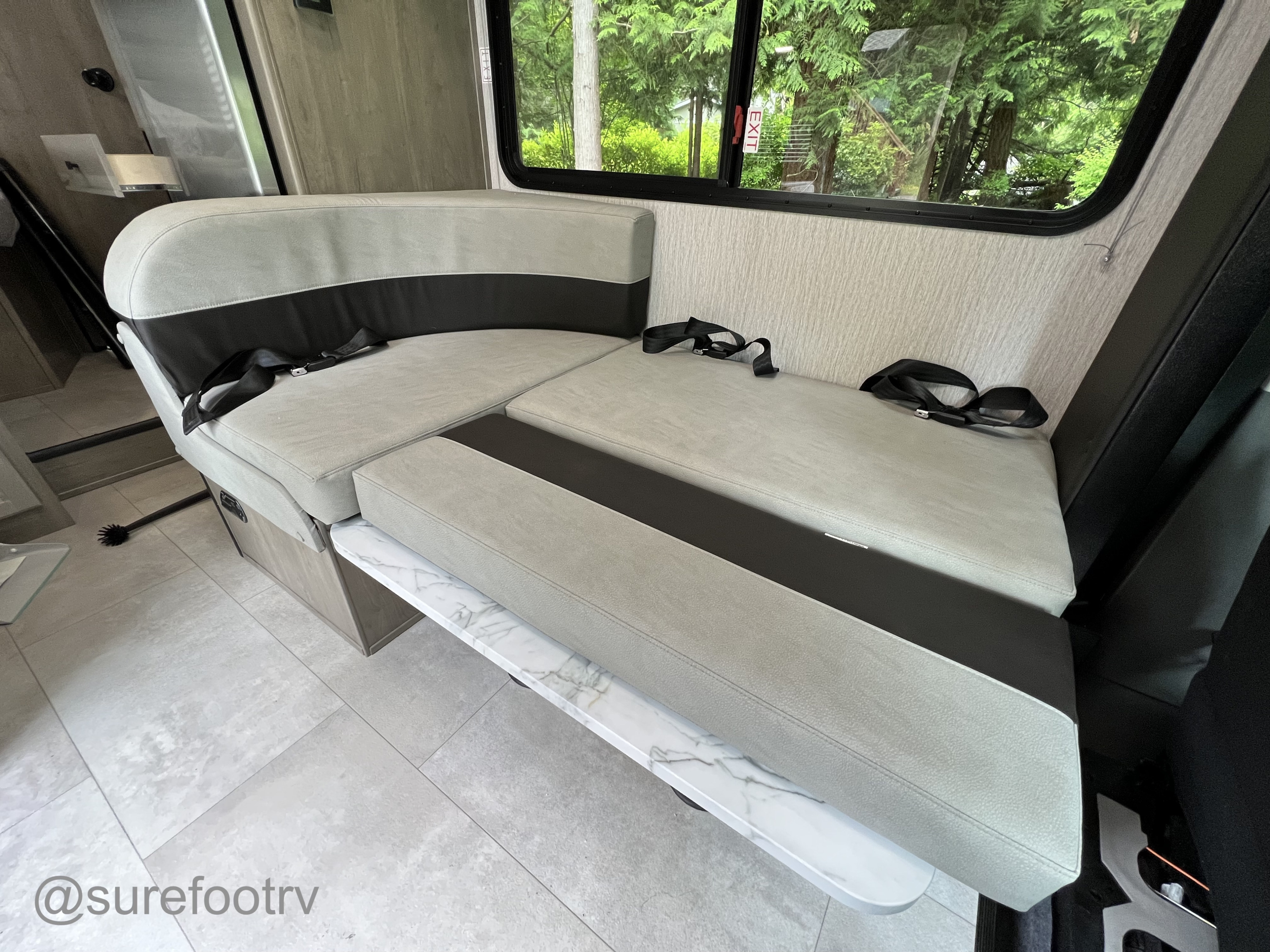 RV rental interior: light grey dinette with black accents & seatbelts, ready to convert to a bed with a marble-patterned table.. Forest River Coachmen Cross Trail XL 2022