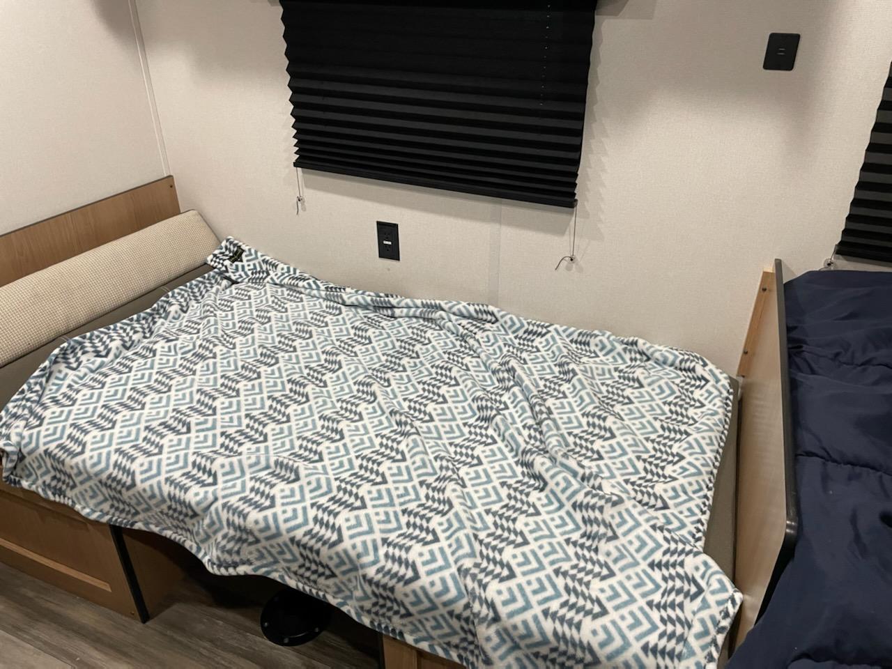 Cozy RV rental bunk bed setup with patterned blanket and adjacent sleeping area, perfect for family adventures.. Prime Time Avenger 2022