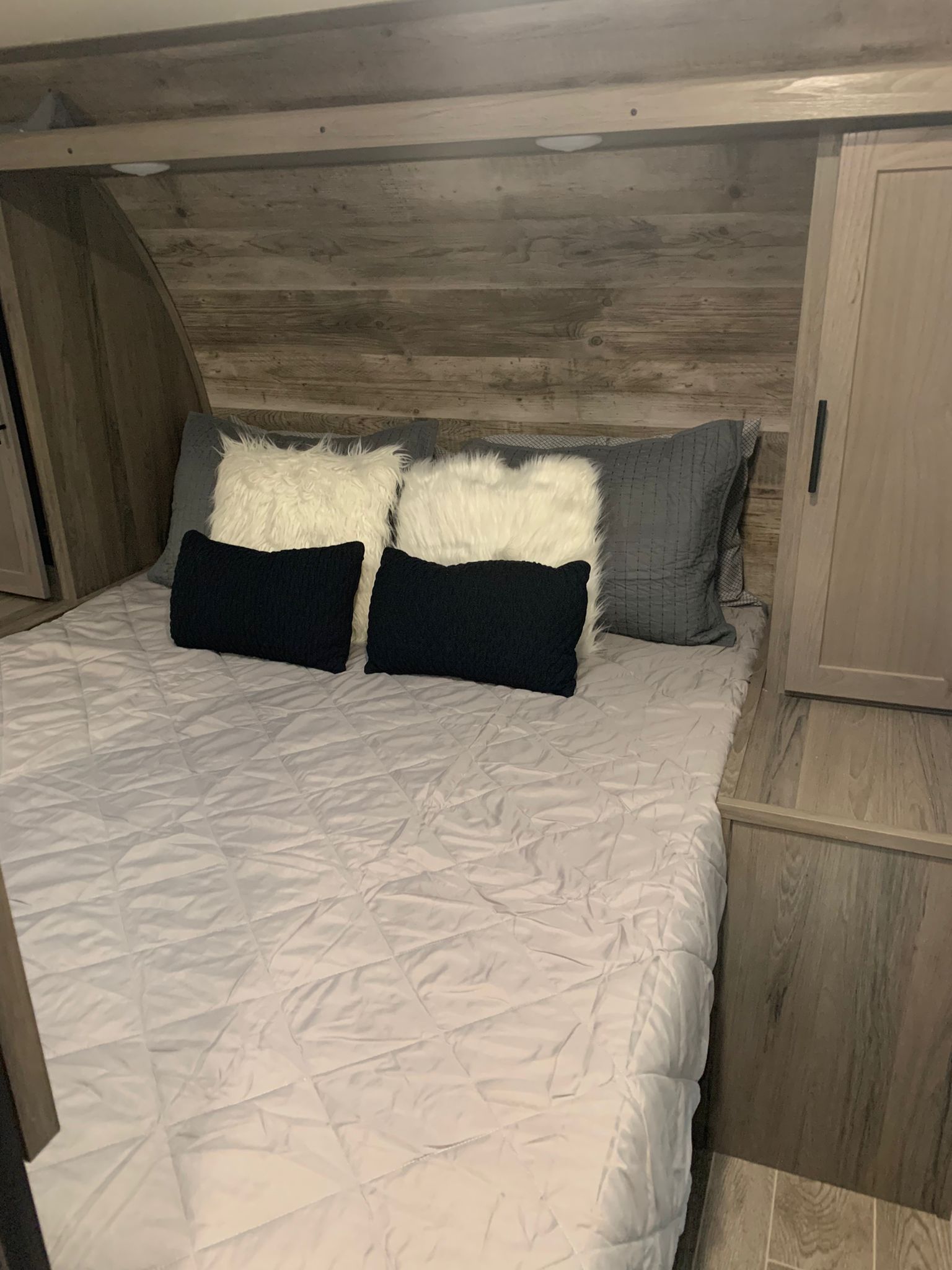 Cozy RV rental bedroom with light gray bed, fluffy pillows, and modern wood paneling.. Gulf Stream Ameri-Lite 2021