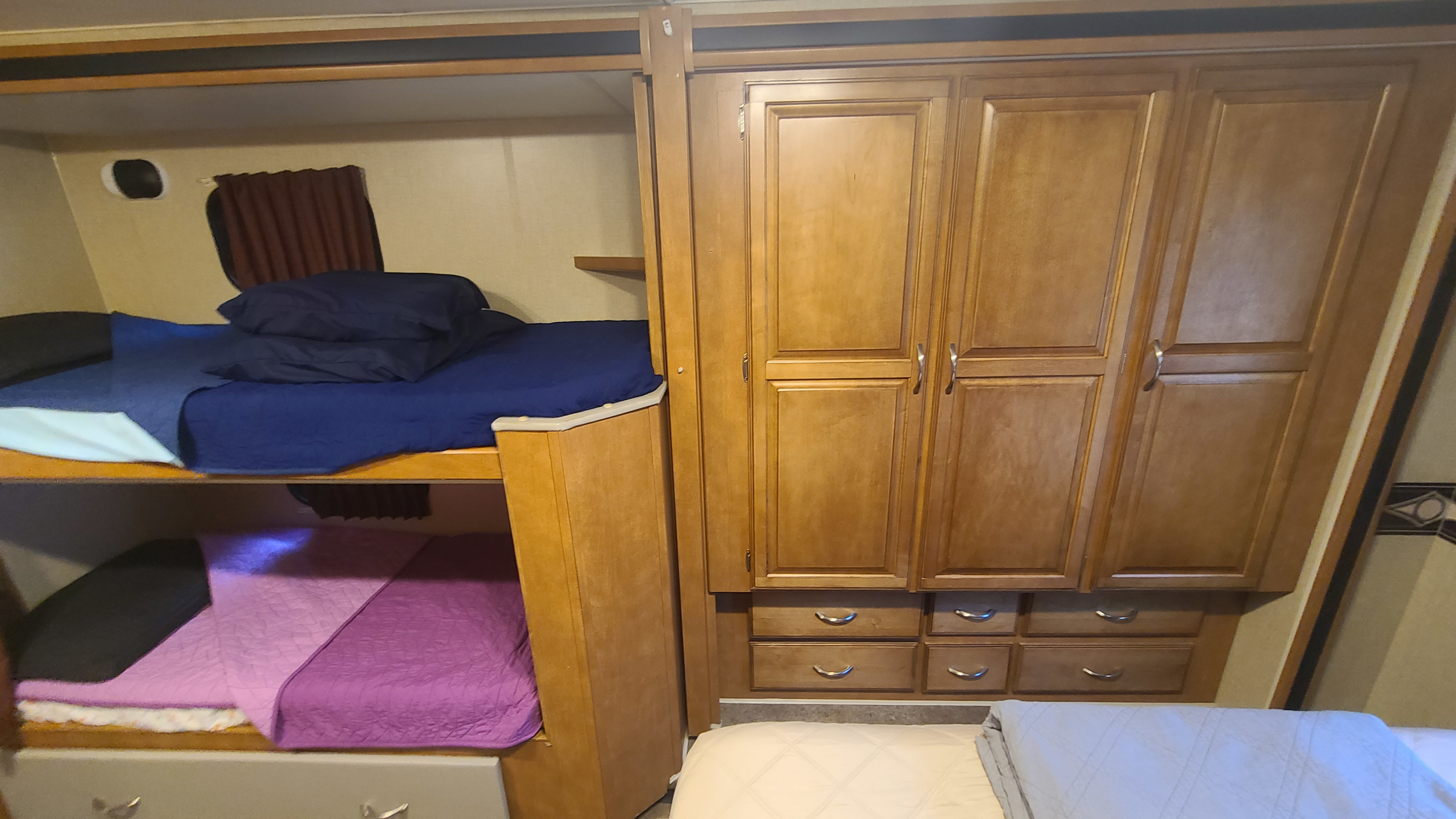 RV rental interior: cozy bunk beds with blue/purple bedding & wood cabinets for storage.. Winnebago Minnie Winnie 2017