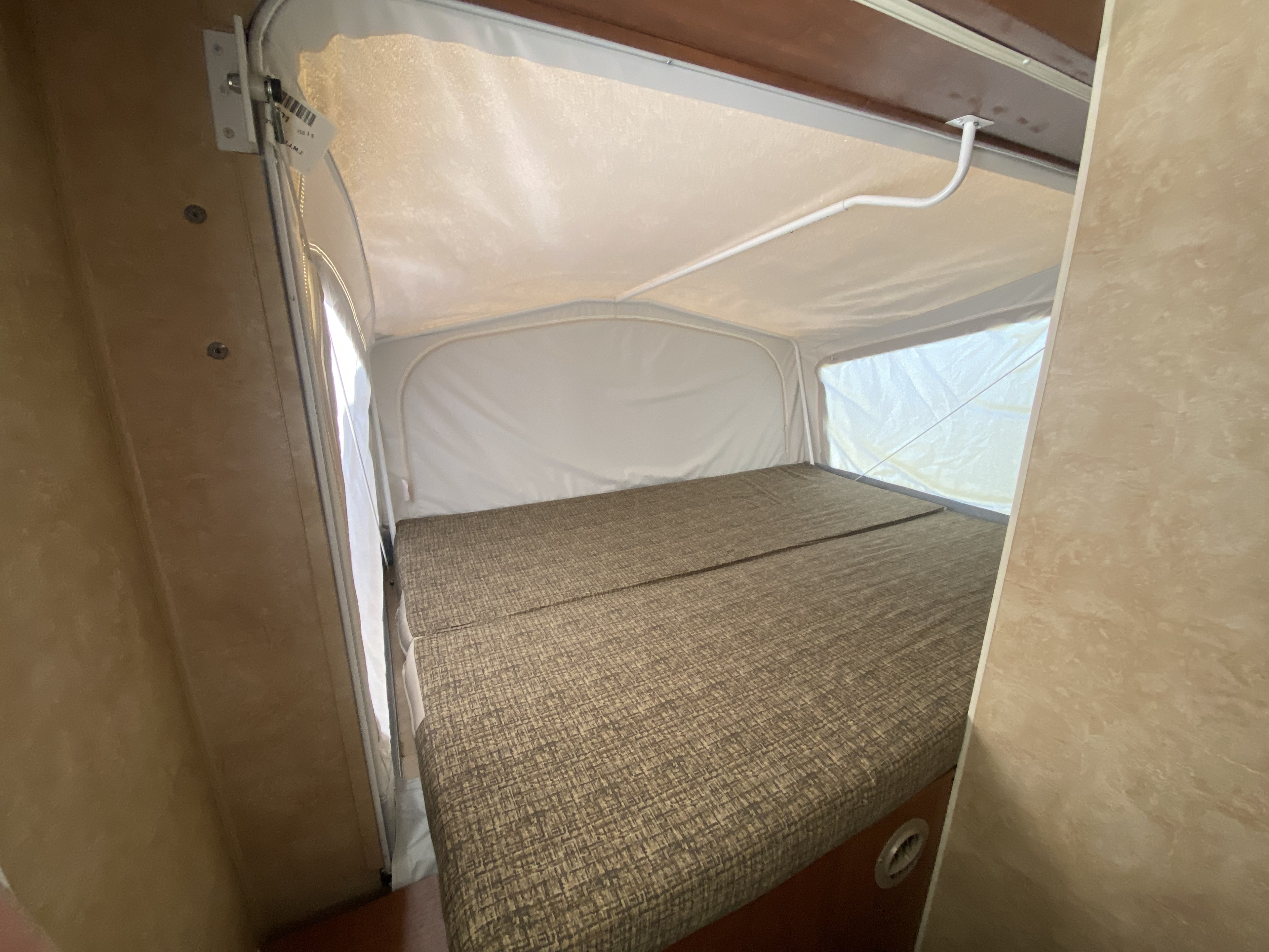 Cozy RV rental pop-up camper interior with large bed and light canvas walls for comfortable sleeping.. Jayco Jay Feather Sport EXP 2011
