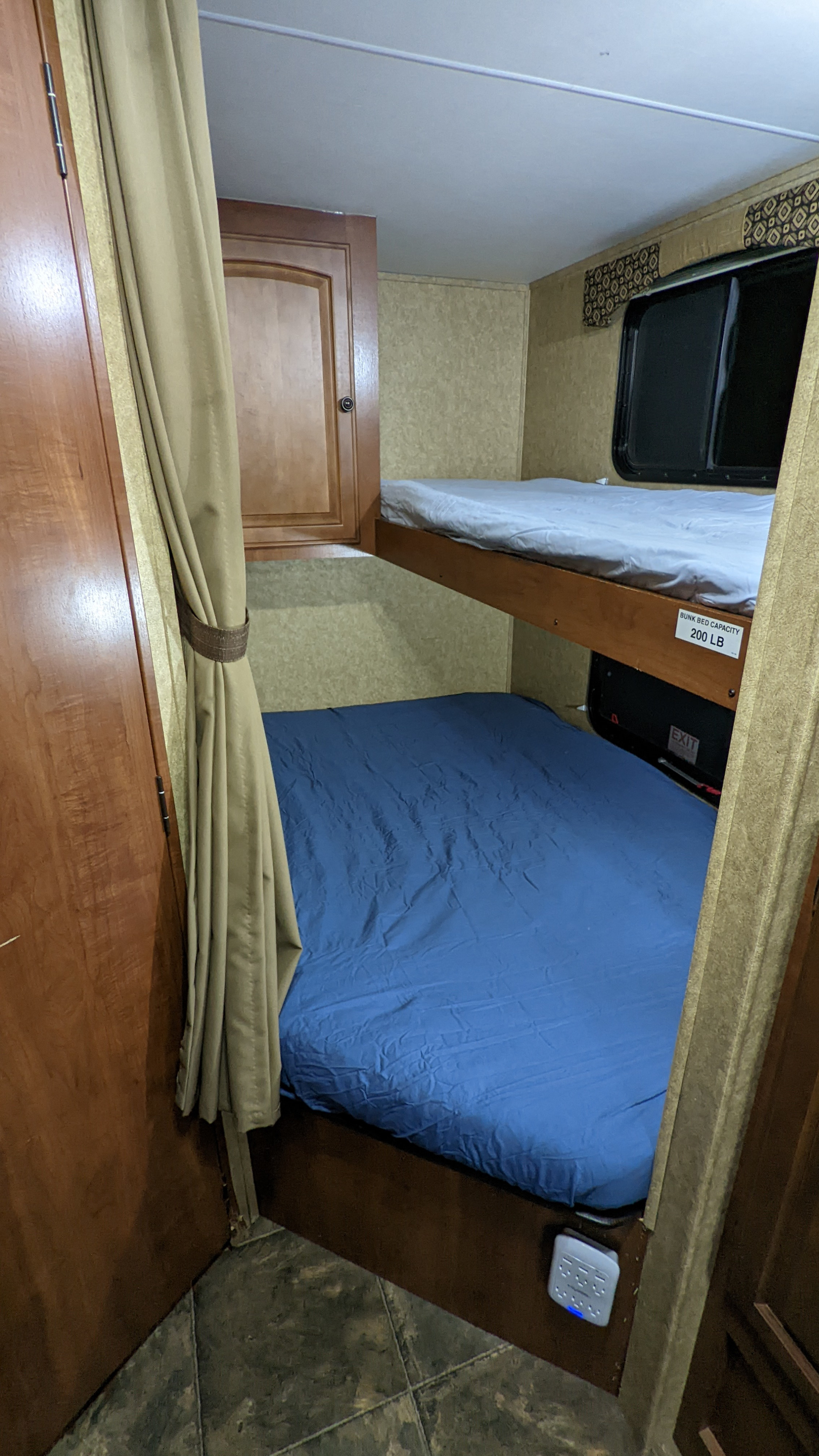 Cozy bunk beds inside an RV rental, with blue & grey sheets. The top bunk capacity is 200 lbs.. Heartland RVs North Trail 2013