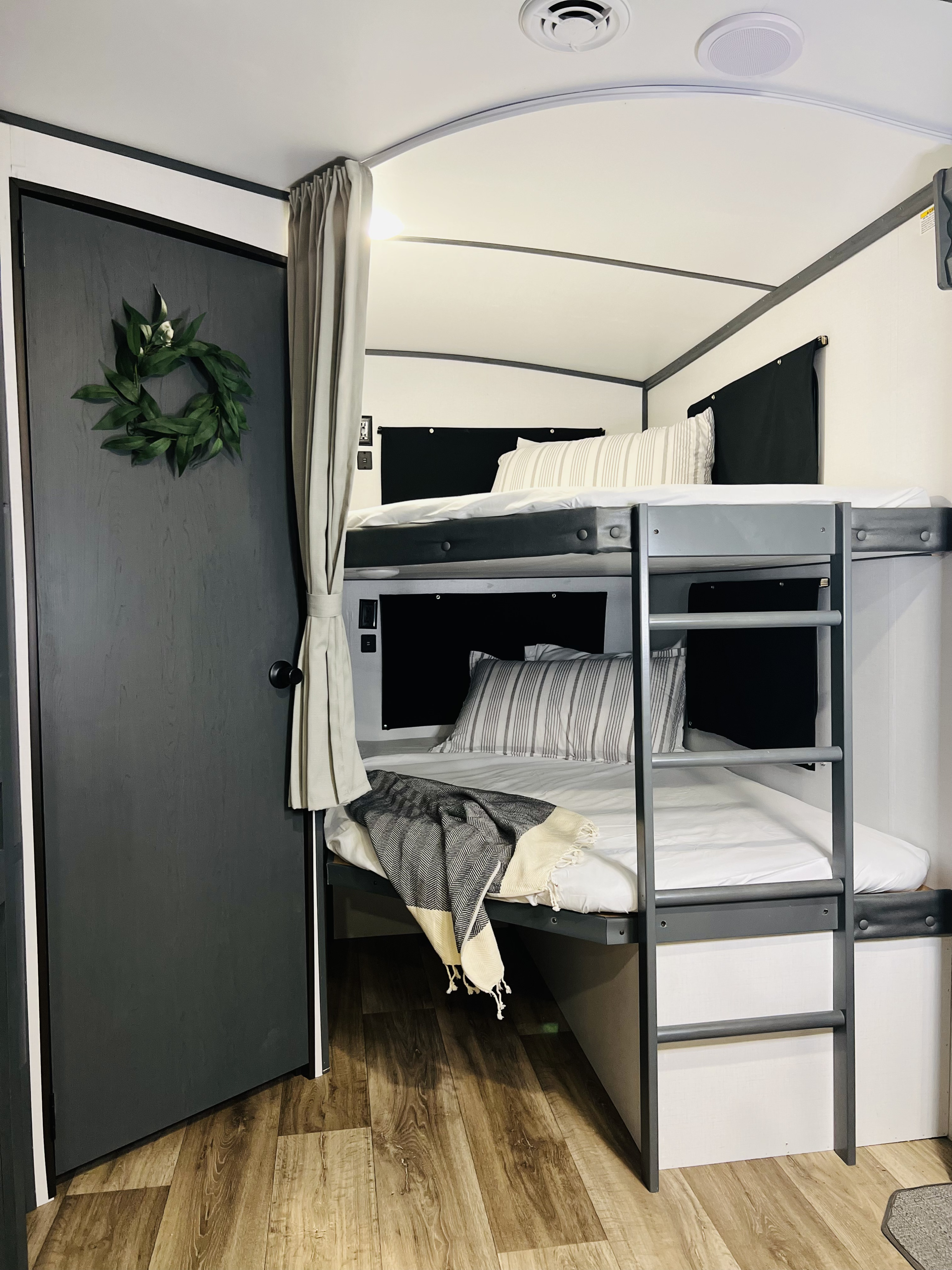Modern RV rental interior features comfy bunk beds, wood flooring, and a decorative door. Ready for travel!. Keystone Bullet 2022