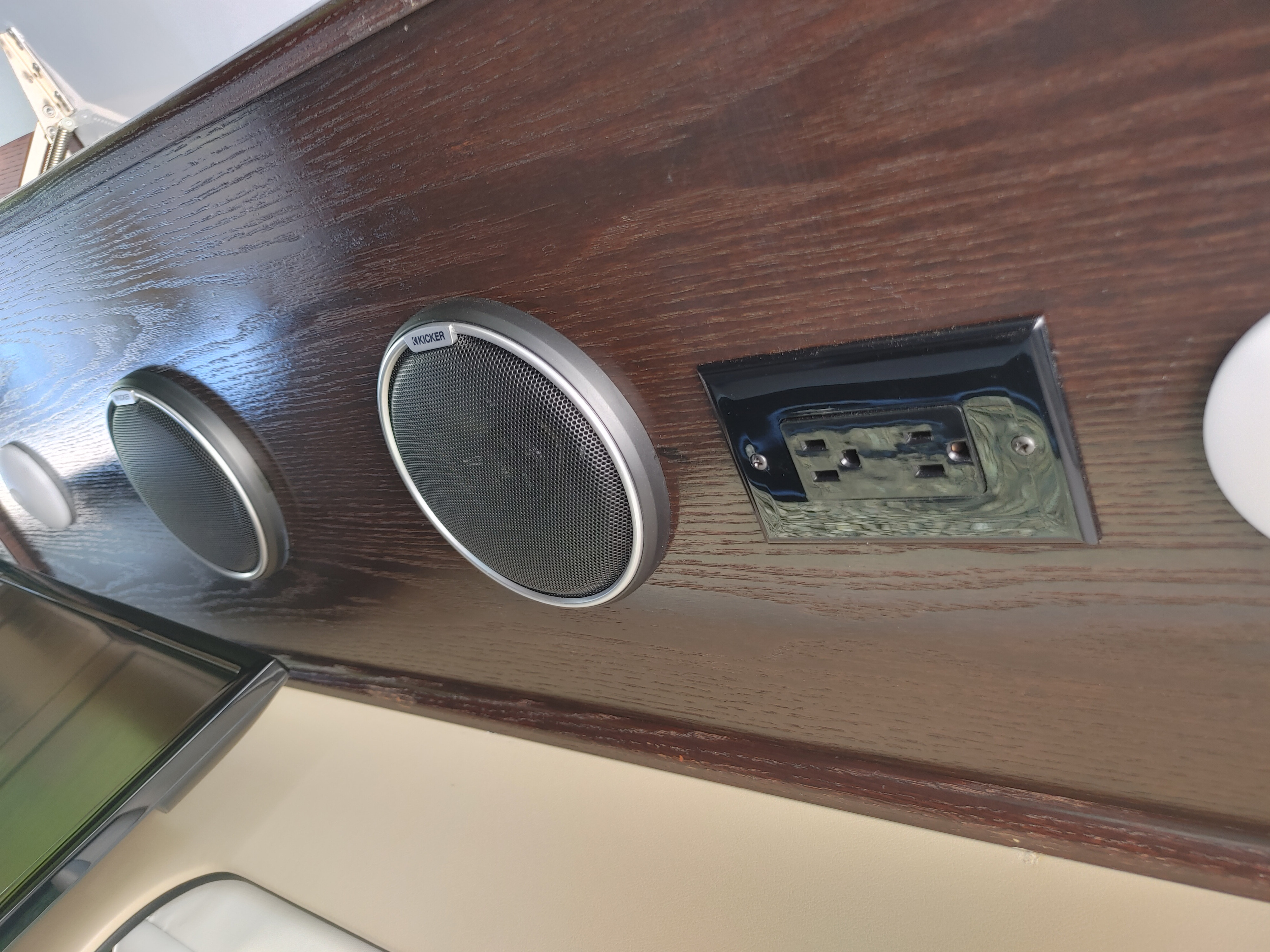 Kicker speakers and electrical outlet mounted on wood paneling inside an RV rental.. Regency RV National Traveler 2019