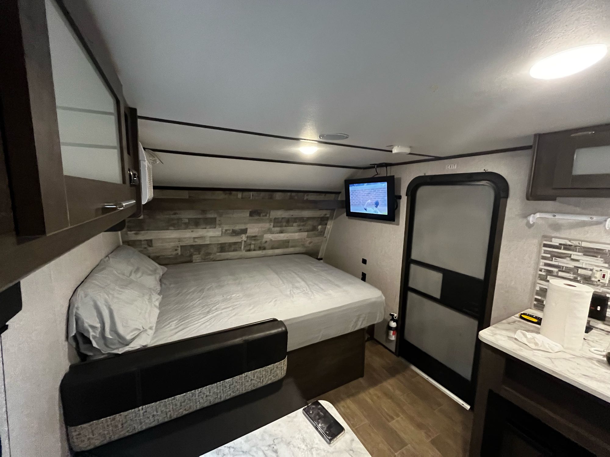Cozy RV rental interior showcasing a comfortable bed, sofa, wall-mounted TV, and functional counter.. Coleman CM17B21 2021