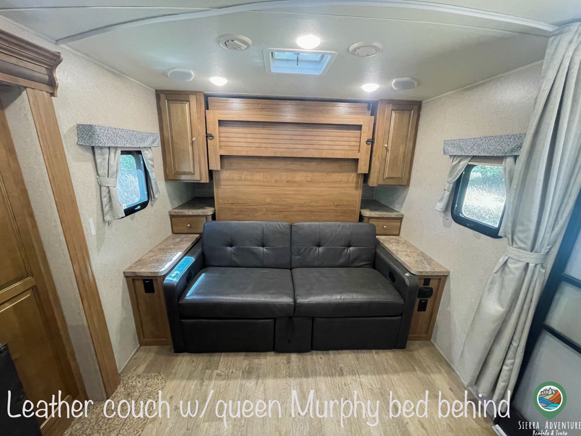 RV rental interior: A black leather couch in front of a hidden queen Murphy bed offers practical, convertible sleeping space.. Forest River Rockwood Mini Lite 2019