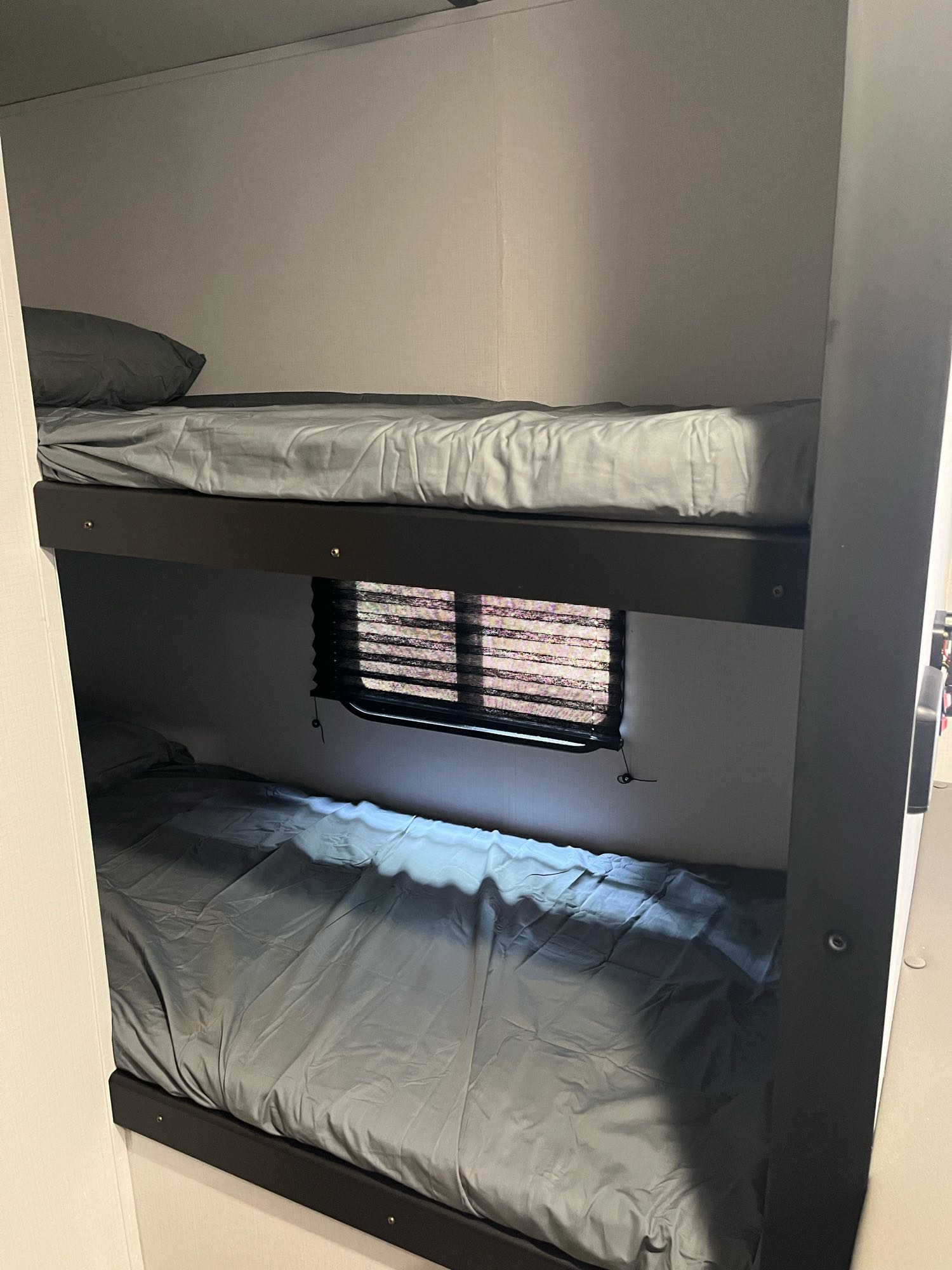 Cozy RV rental bunk beds with gray bedding and a window, perfect for comfortable travel accommodation.. Keystone RV Springdale 2022