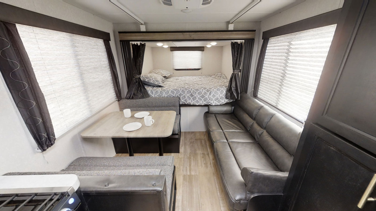RV rental interior: inviting living space with a bed, dinette, sofa, and a peek at the kitchen. Compact & ready for adventure.. Forest River Cherokee Grey Wolf Special Edition 2020