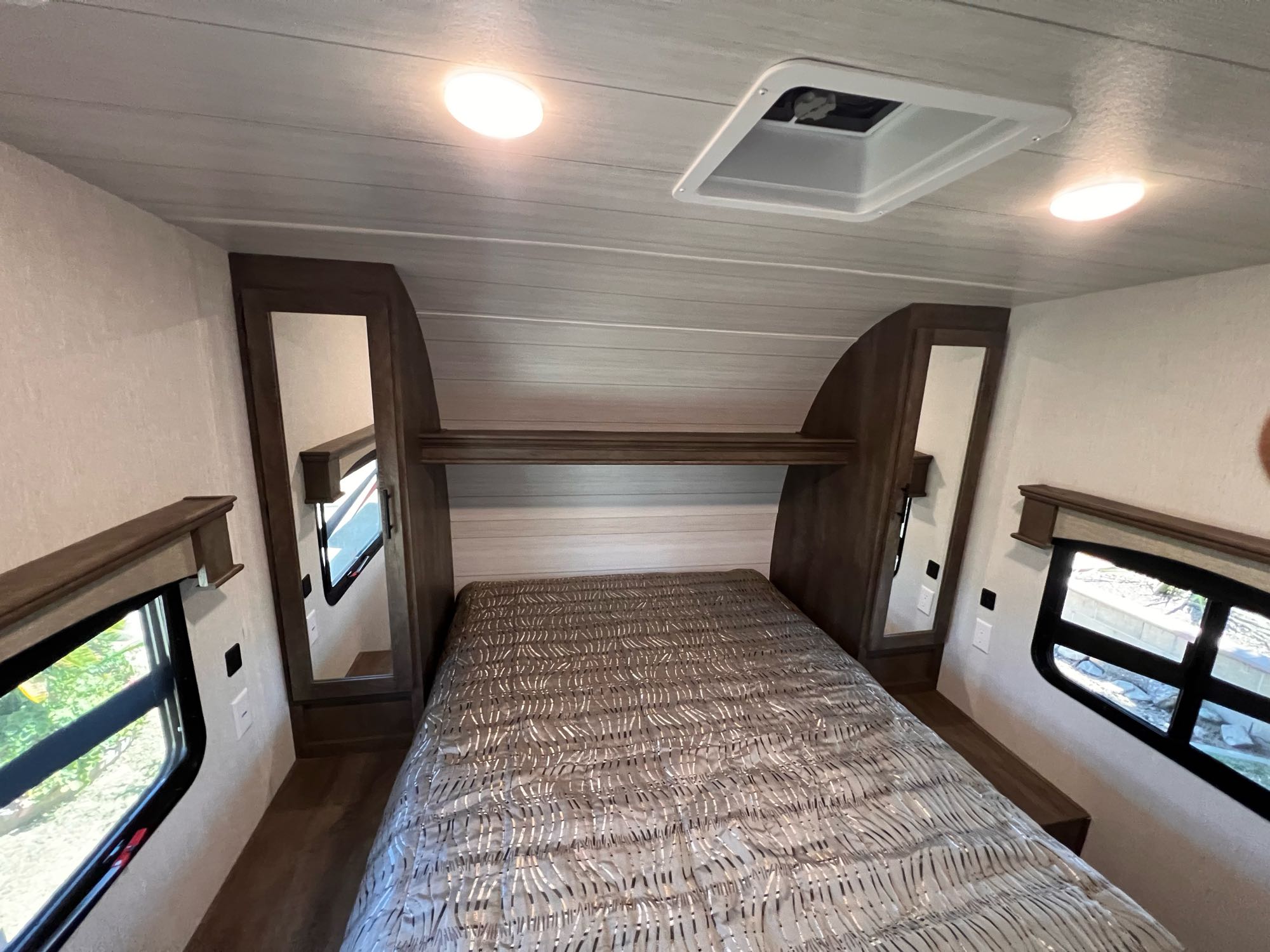 Compact RV rental bedroom featuring a bed, overhead lights, and side windows for a cozy stay.. Forest River Shockwave 2022