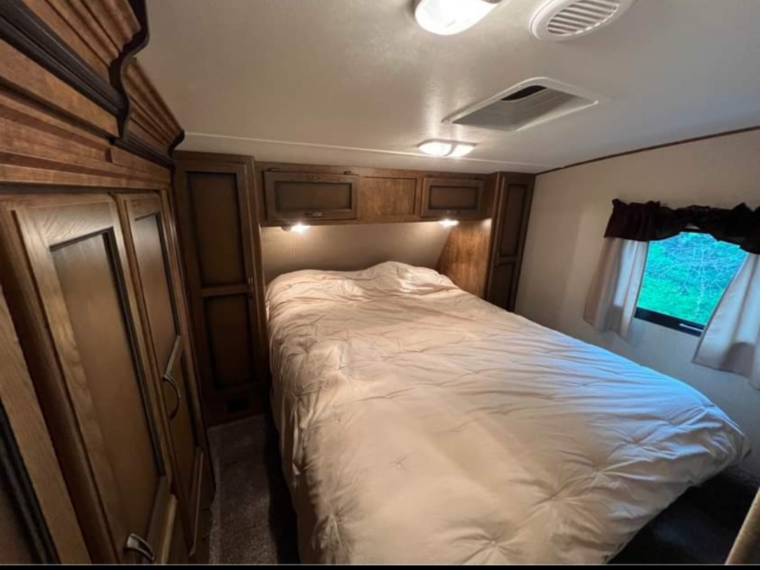 Cozy RV rental bedroom with a comfortable bed, built-in storage, and natural light from windows.. Crossroads RV Rezerve 2016