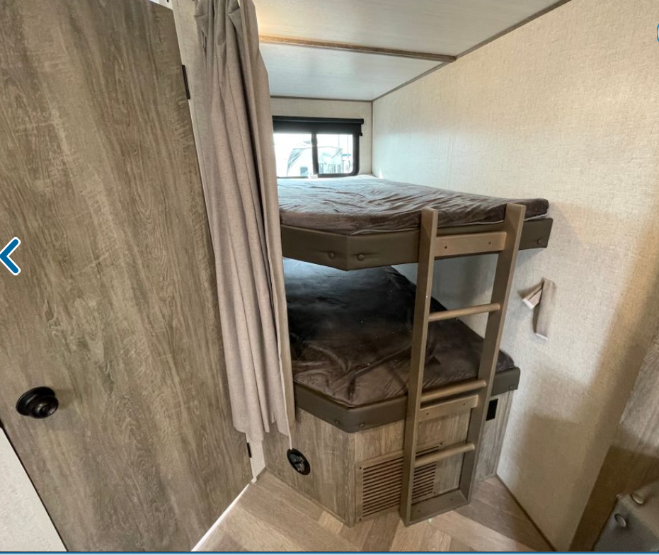 RV rental: Compact bunk beds with dark bedding and a ladder in a wood-paneled interior.. Forest River Wildwood Heritage Glen 2022