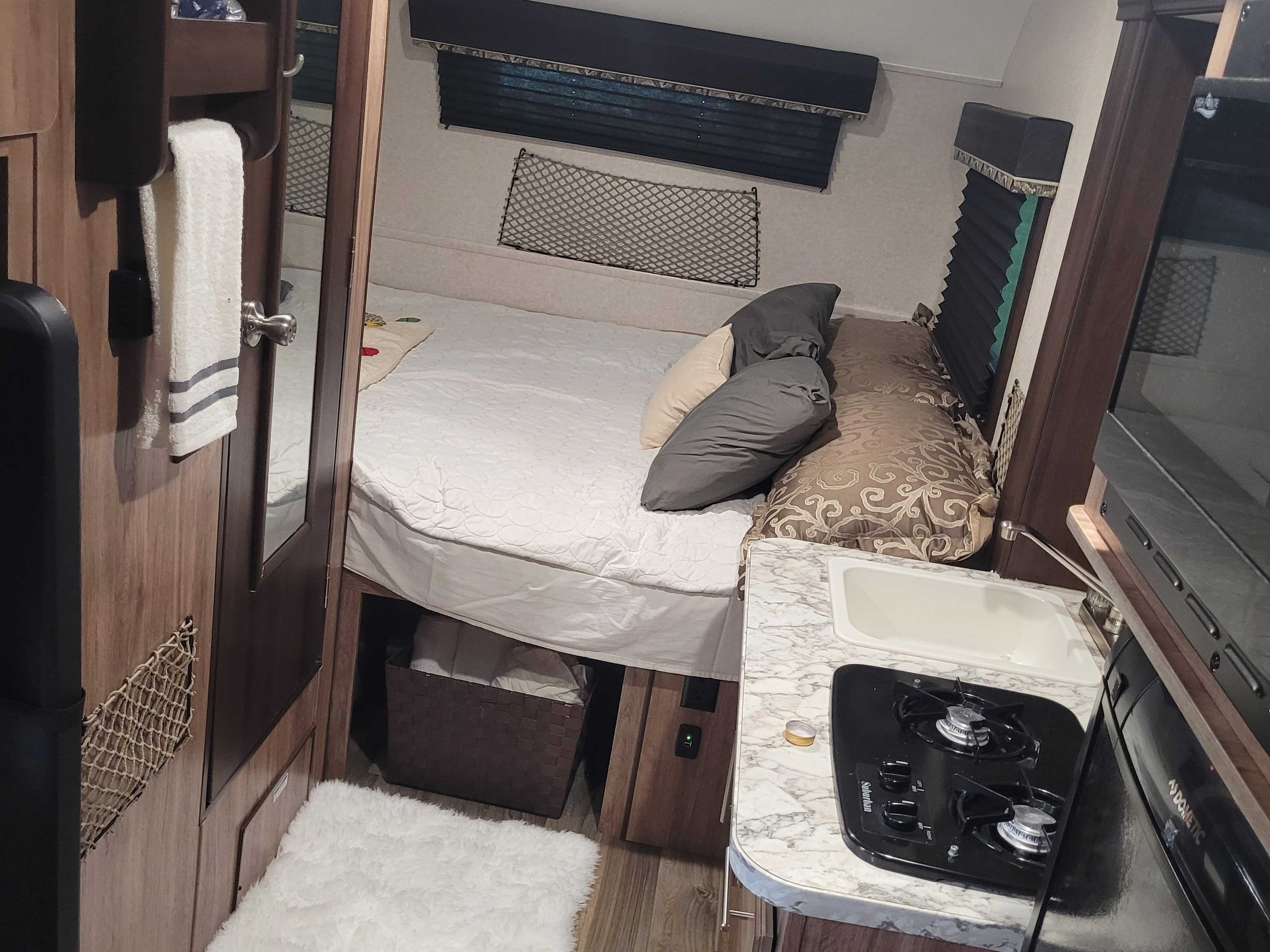 This RV rental offers a cozy bedroom area with a bed, and a compact kitchen featuring a sink and two-burner stove.. Jayco Hummingbird 2018